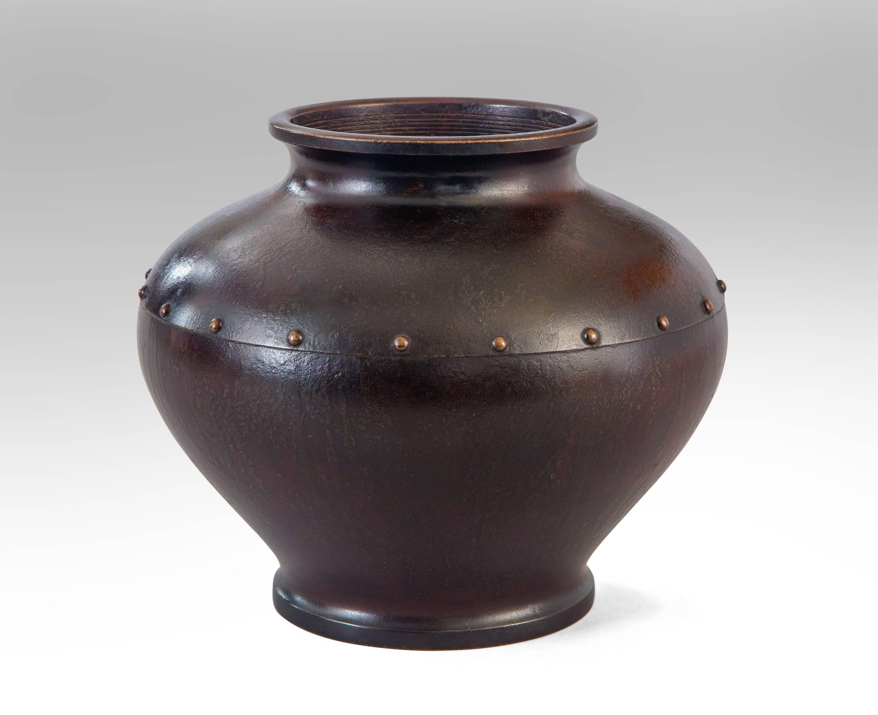 A highly unusual form simulating riveted construction.The circular flared mouth, above a jar form body divided by a line of studs, terminating in a circular foot, enhanced with a rich green brown patination throughout.

This Japanese Bronze Vase in