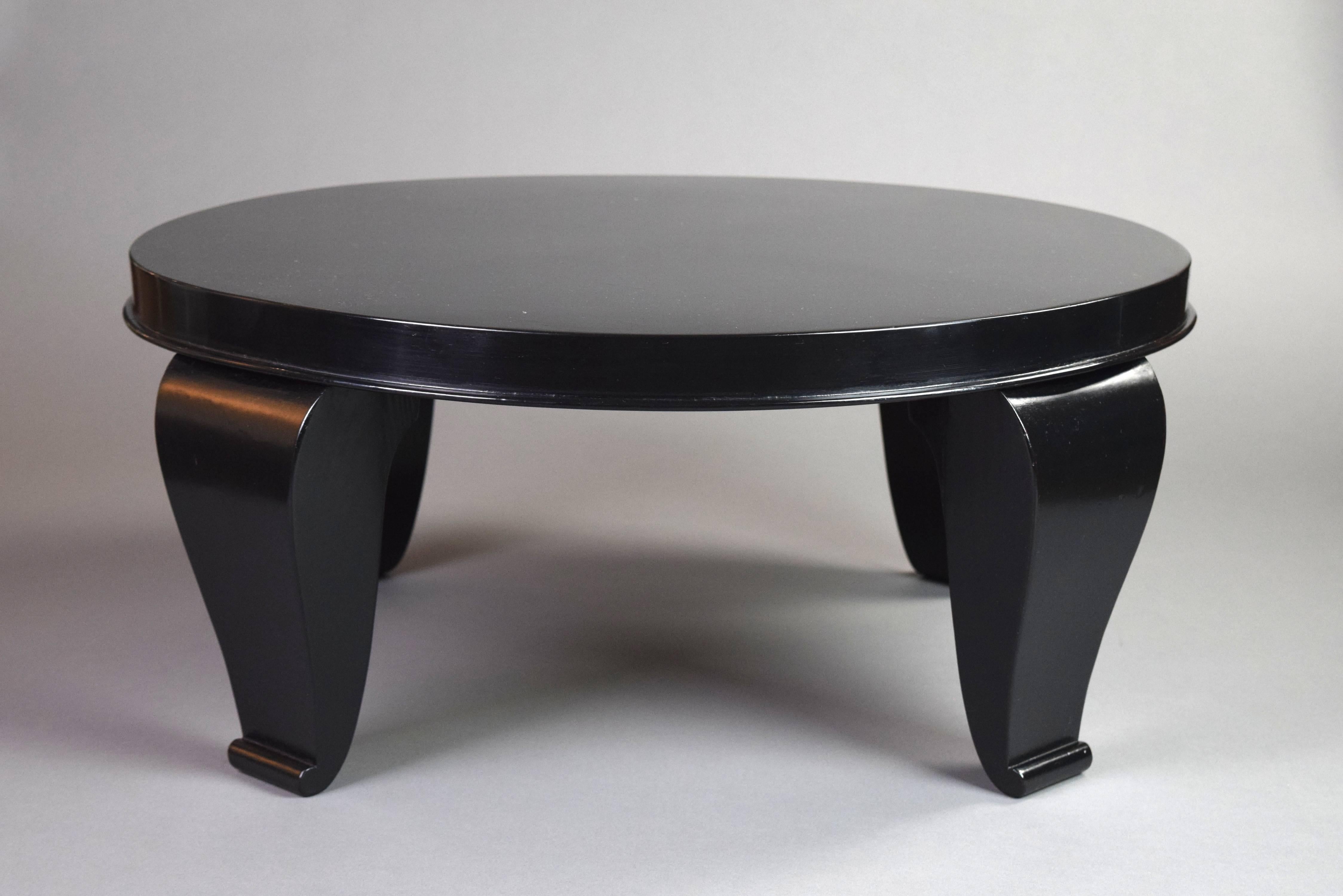 The circular top with molded edge above four tapering curved legs with scroll feet.