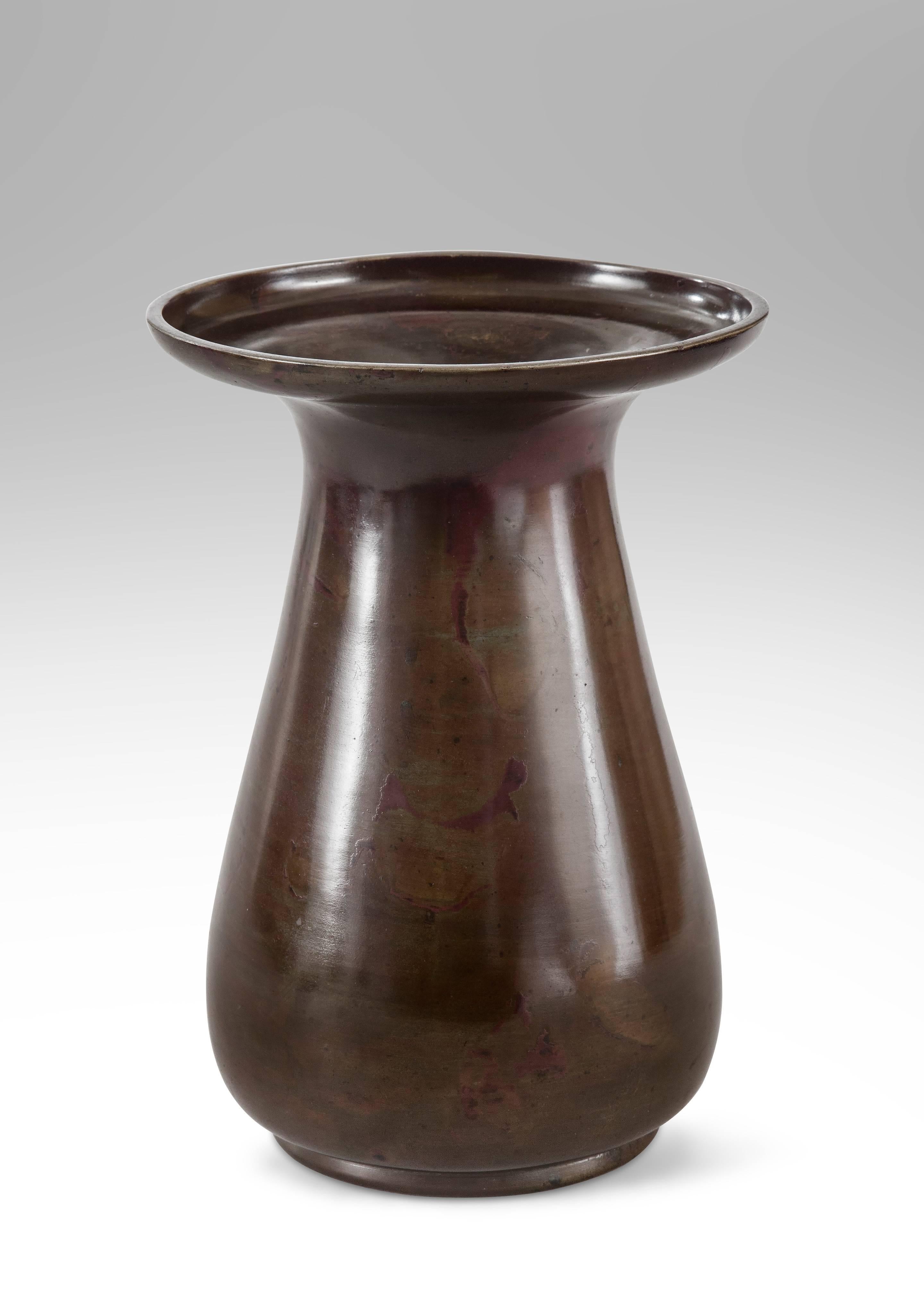Of a beautifully mottled patination and a sensuous form. The outflared rim above the pear shape body on a circular base. A rare vase that can be reversed with both the top and bottom with openings.

This handsome Japanese bronze vase in very good