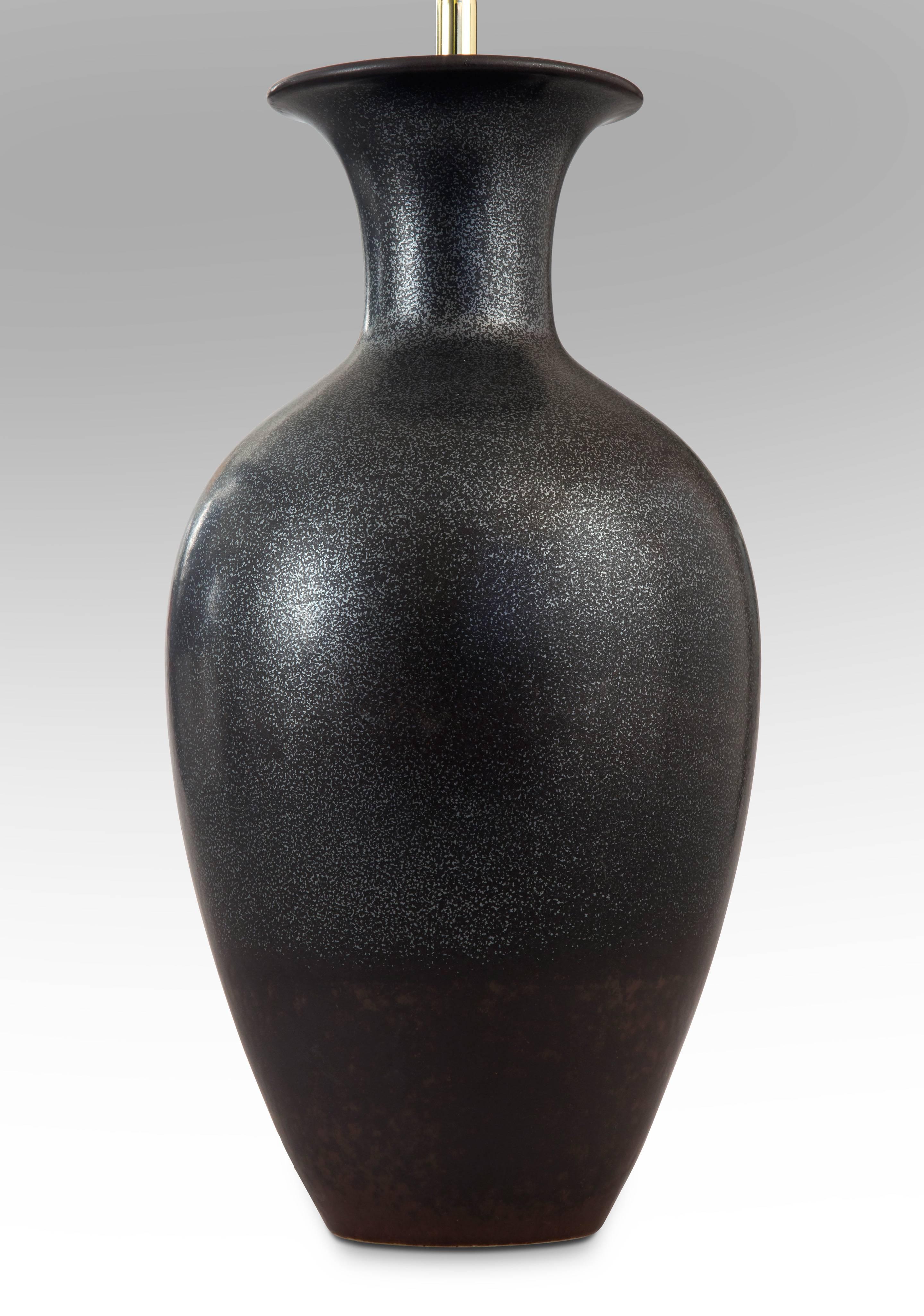 The flared neck above an elegant, high shouldered ovoid body, the upper part with speckled graphite glaze and the bottom portion a rusty-brown glaze. 

Very good condition and ready to add to your collection. Museum wired, not drilled, lamp can