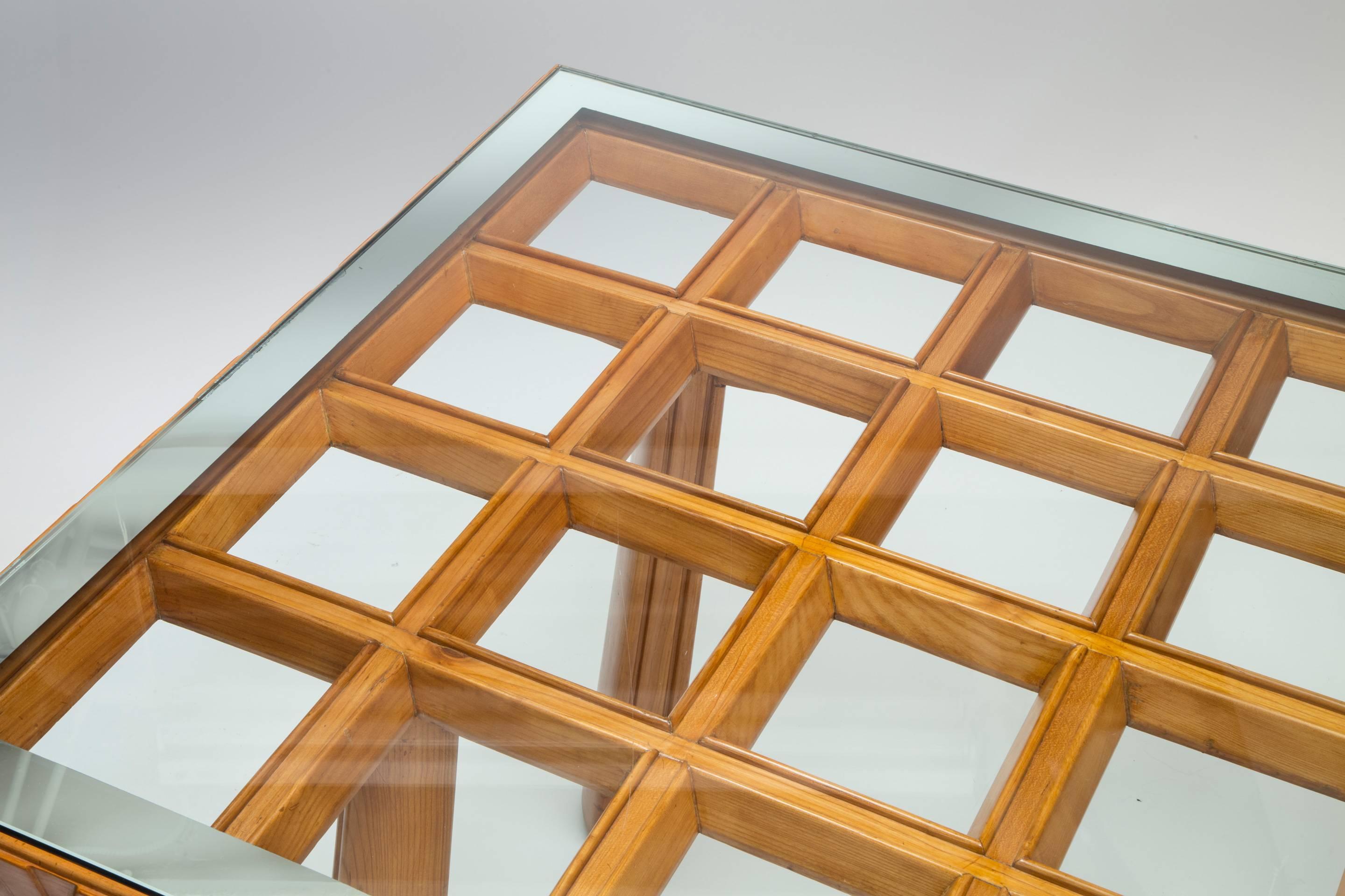 A sophisticated and exceptional work by renowned designer Osvaldo Borsani. The rectangular glass top with mirror border, resting on a grid of open squares, the frieze displaying a stylized wave pattern, above tapering oval legs, each split by single