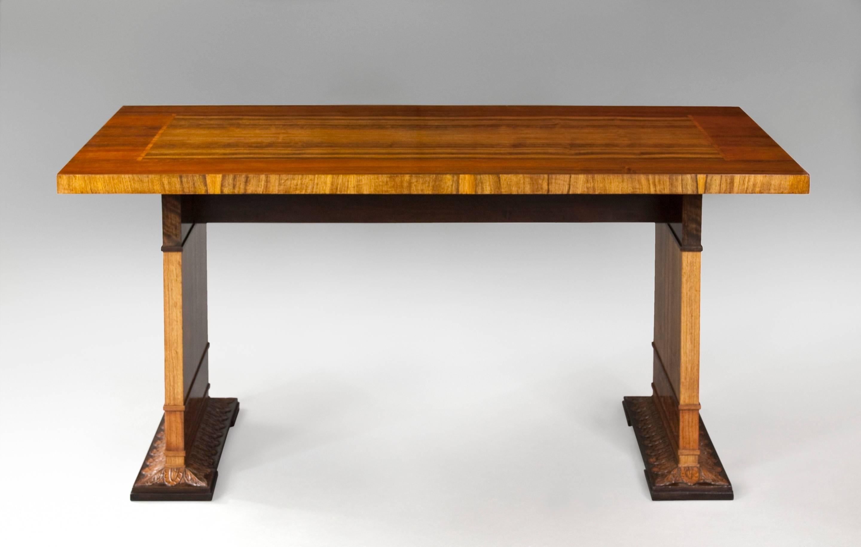 Beautiful table with stunning woods and classic design. The rectangular top, centering a book-matched veneer reserve, above two rectangular legs, each adorned in marquetry panels and terminating in podia of carved leaves. 
