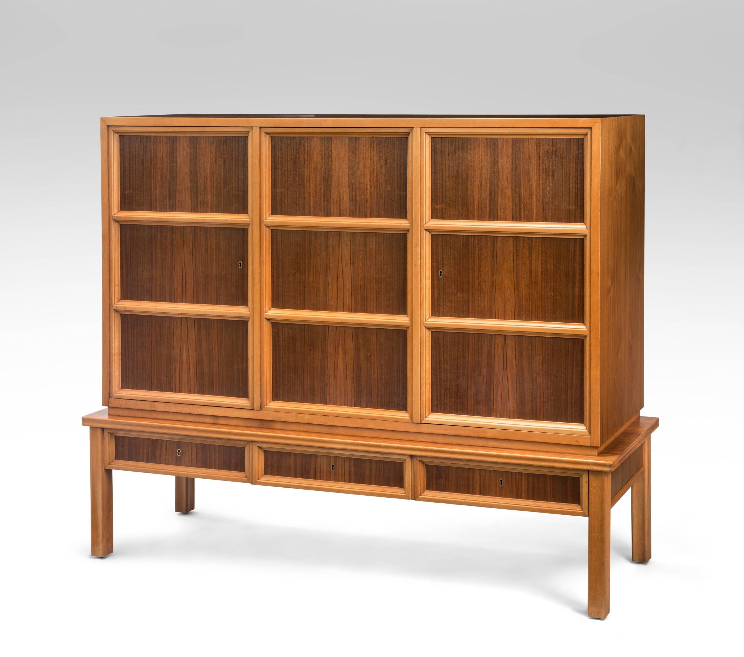 A very handsome cabinet composed of beautifully figured dark walnut framed by light color beech. The rectangular top, above a three door cabinet, each door adorned in molding against a rosewood background, above a three drawer lower frieze, the