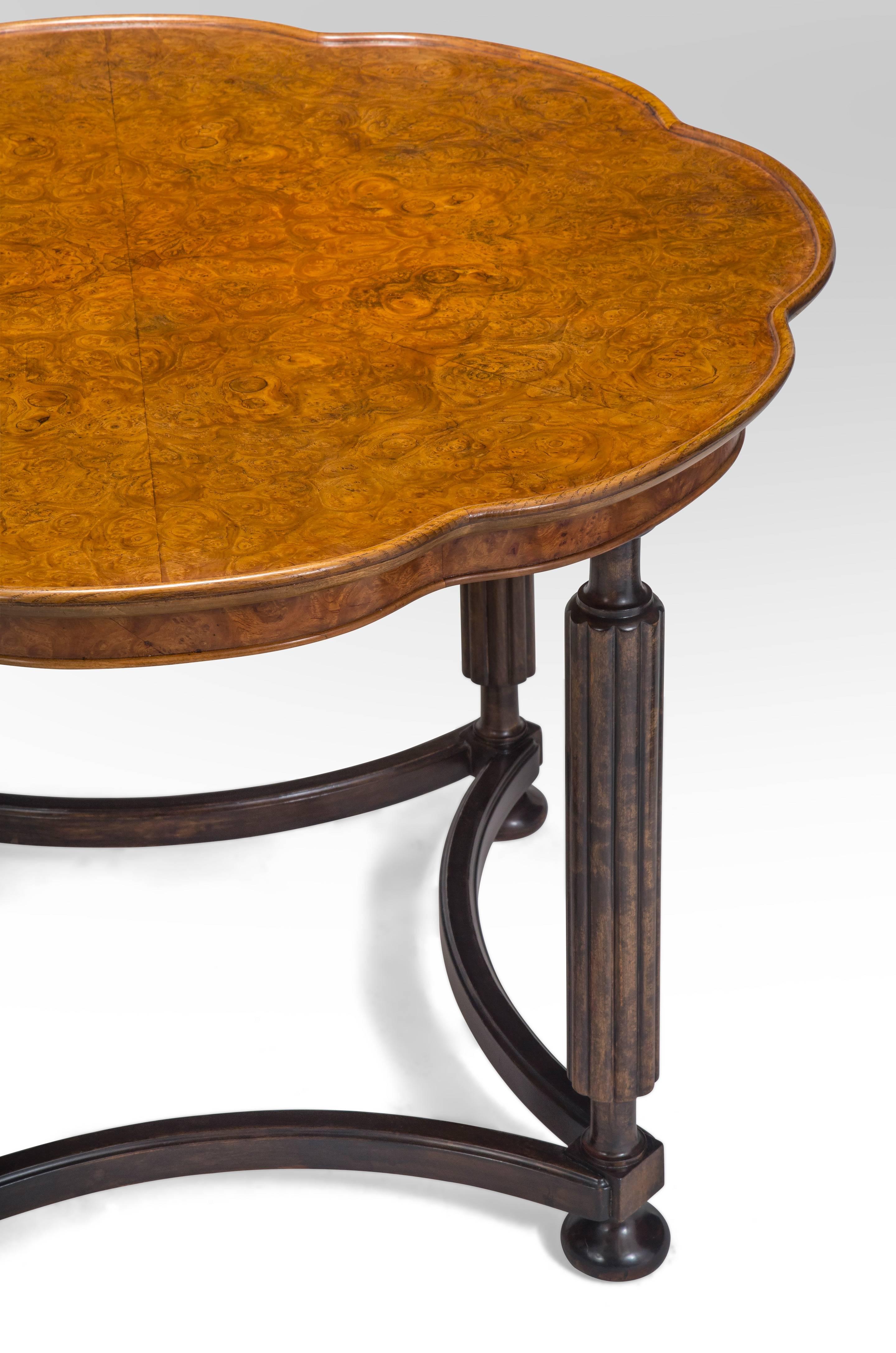 Beautiful table with a lively shaped top and gorgeous burl wood. The octofoil top composed of book-matched burl wood set within a raised molding, on fluted columnar legs connected by concave stretchers, terminating in bun feet. 

In great