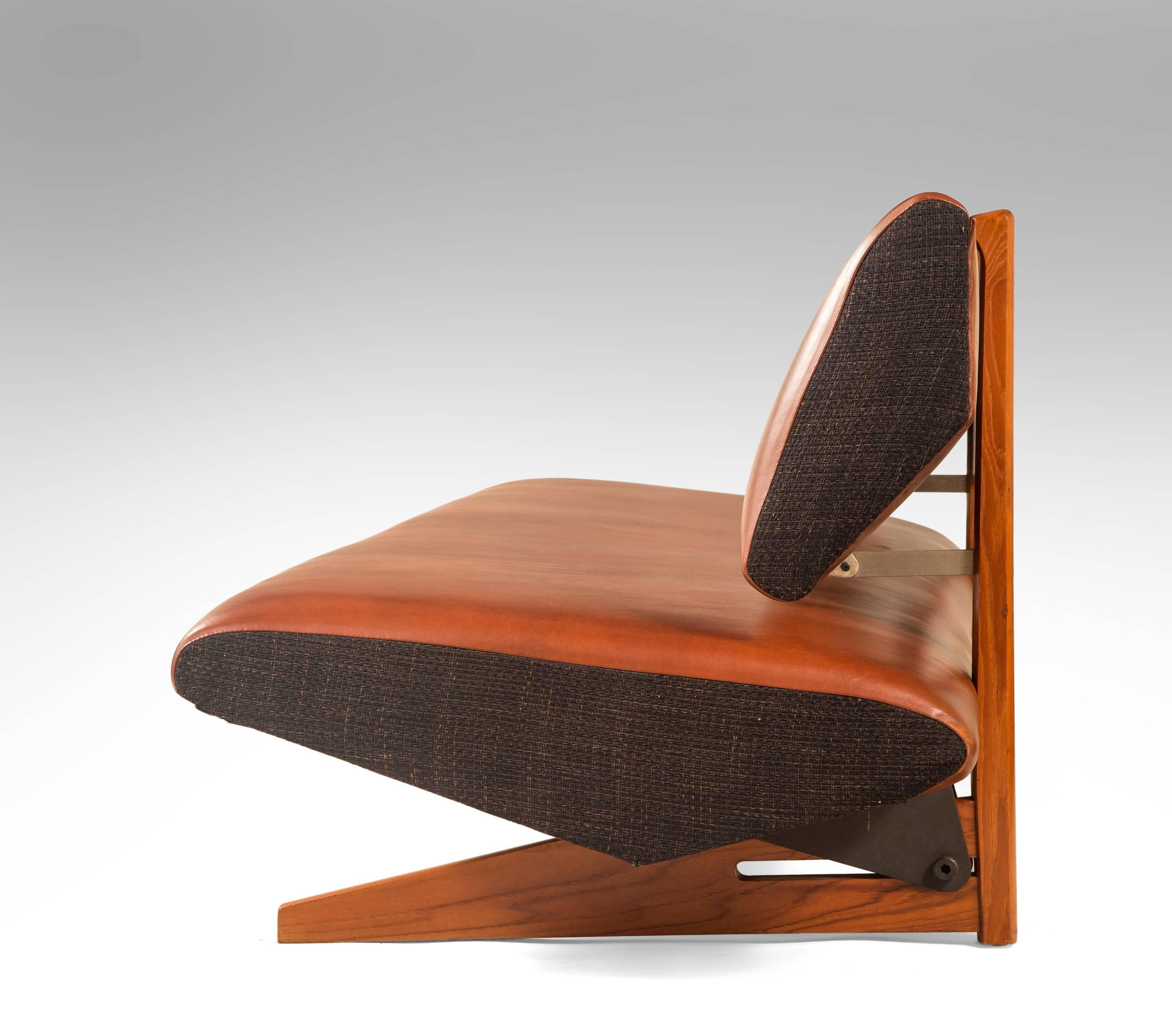 The triangular profiled backrest, floating on teak uprights, above a triangular profiled seat cushion, terminating in two elongated angular feet. Model 701.

The same model sofa is illustrated in Mobilia, 1961