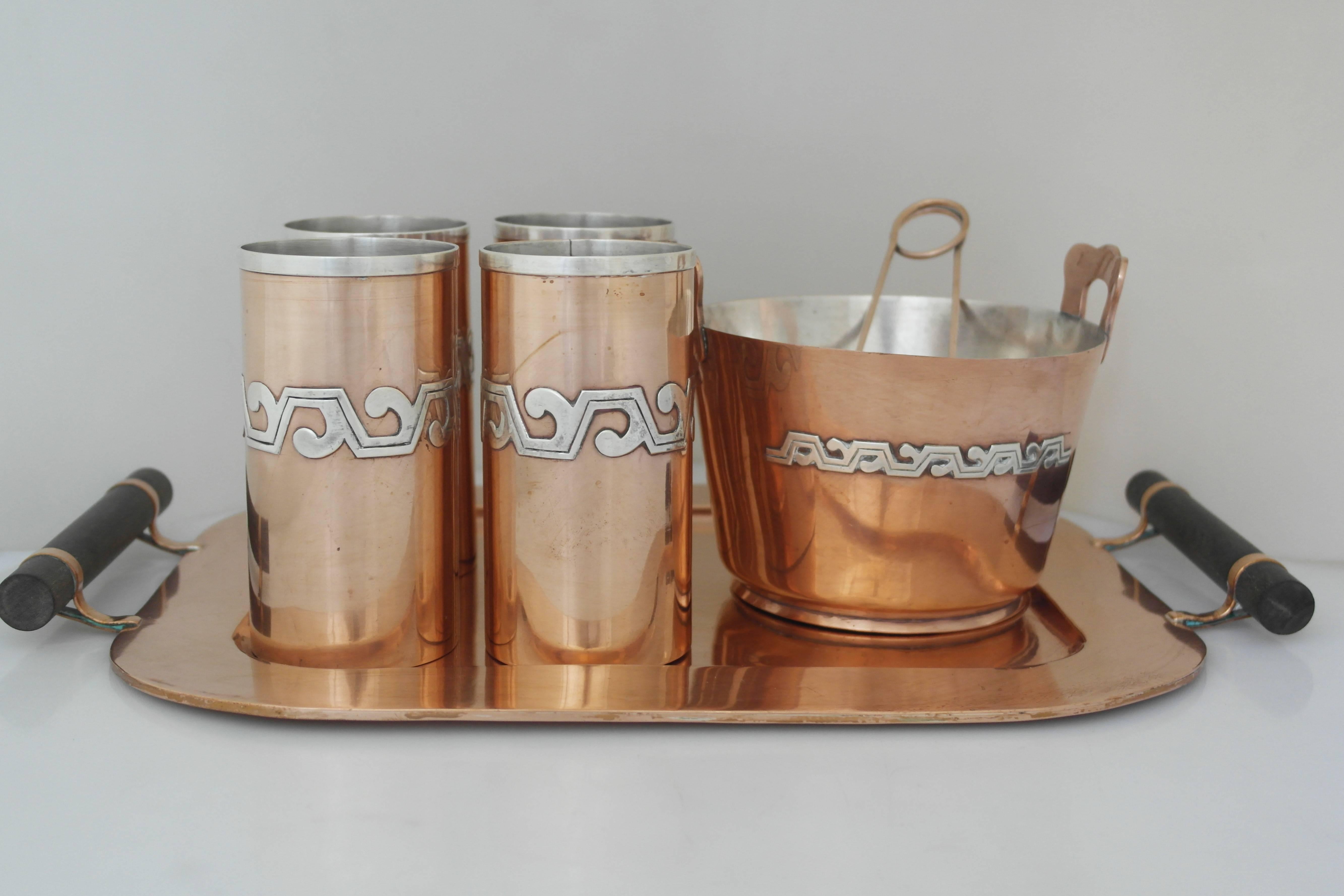 Being offered is a copper and sterling silver drink set by Victoria of Taxco, Mexico. Incredible set includes 4 tumblers, an ice bucket with tongs, and a matching tray with rosewood handle. Entire set is hand-wrought copper with applied sterling