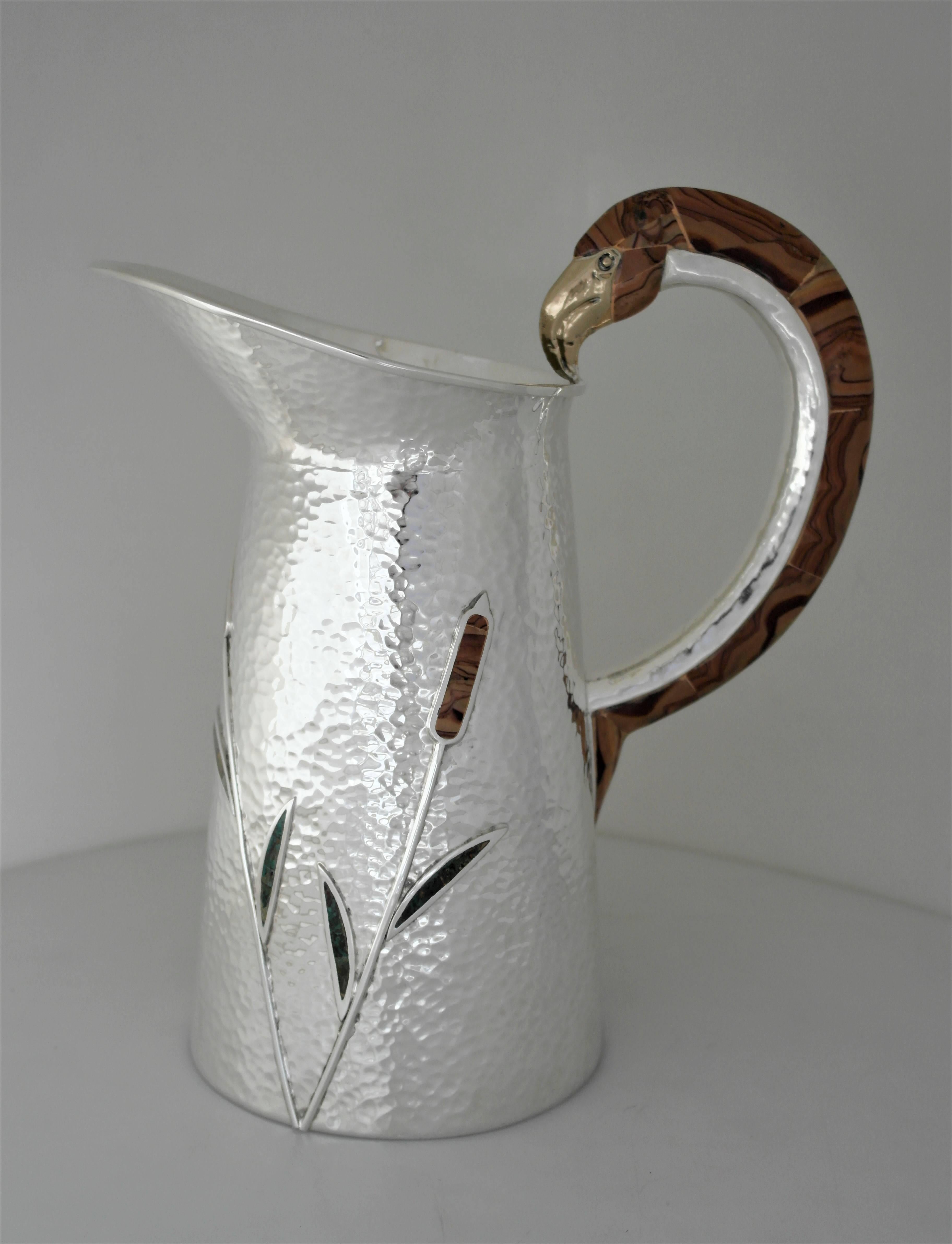 Being offered is a rare circa 1990 large mixed metal and stone silverplate pitcher by Wolmar Castillo of Taxco, Mexico. Handmade piece with cattails and an exotic bird handle decorated with applied natural stone inlay and applied copper. The bird