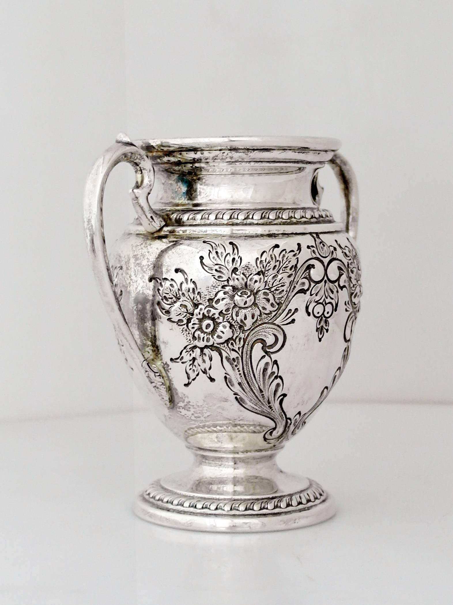 Being offered is a fine, circa 1950 sterling silver vase by Ellmore Silver Co. of Meriden, Connecticut. Urn form with hand chased scrolls and foliate, decorated with two curved handles; resting on a stepped, gadrooned base. Weight 13 ozs.