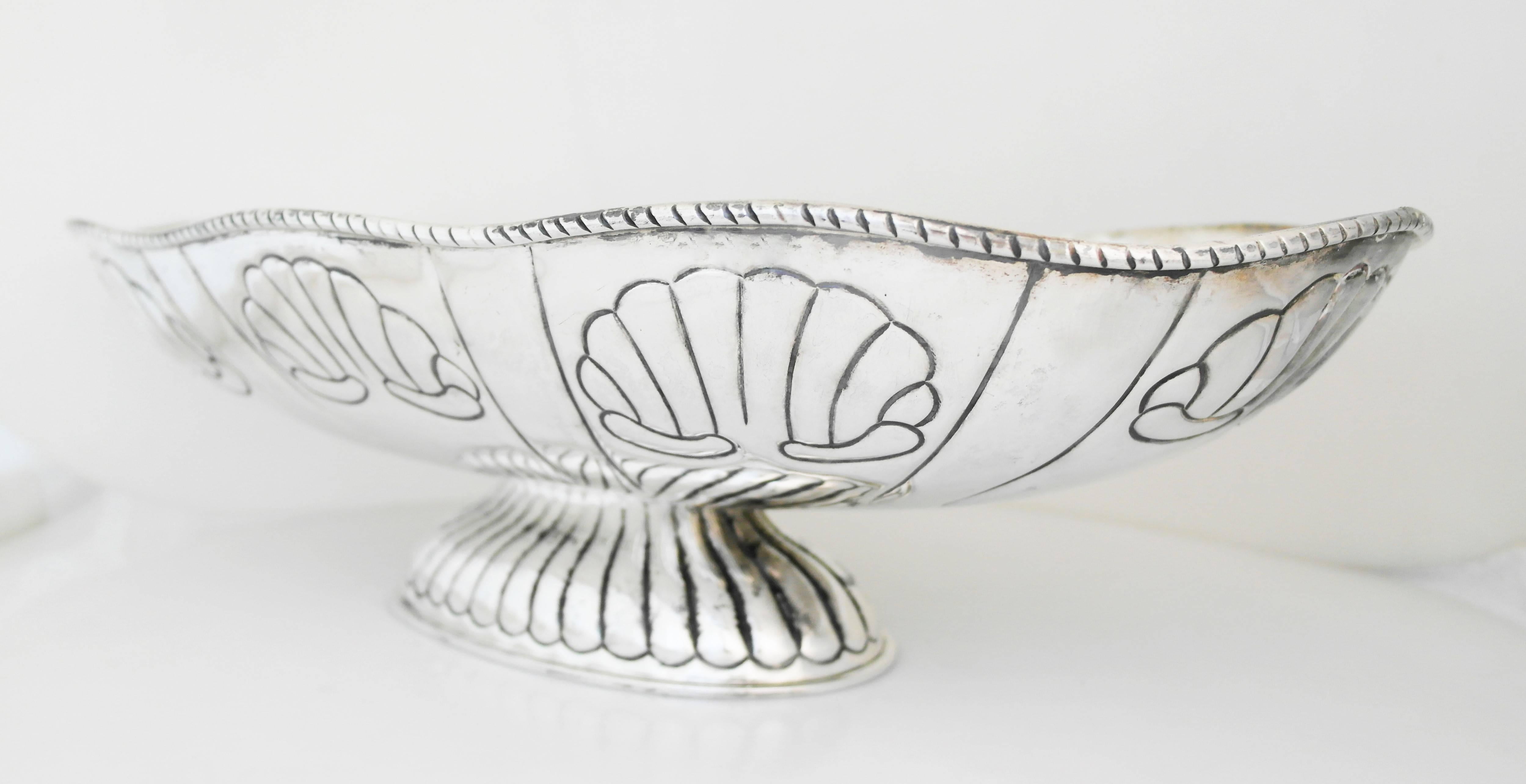 Being offered is a large centerpiece bowl by Tane of Mexico City. Oblong shape, decorated with shell motifs; hand wrought decorated rim; the massive bowl is supported by a reeded pedestal base. Dimensions: 22" x 11" x 6" weight 92 oz.