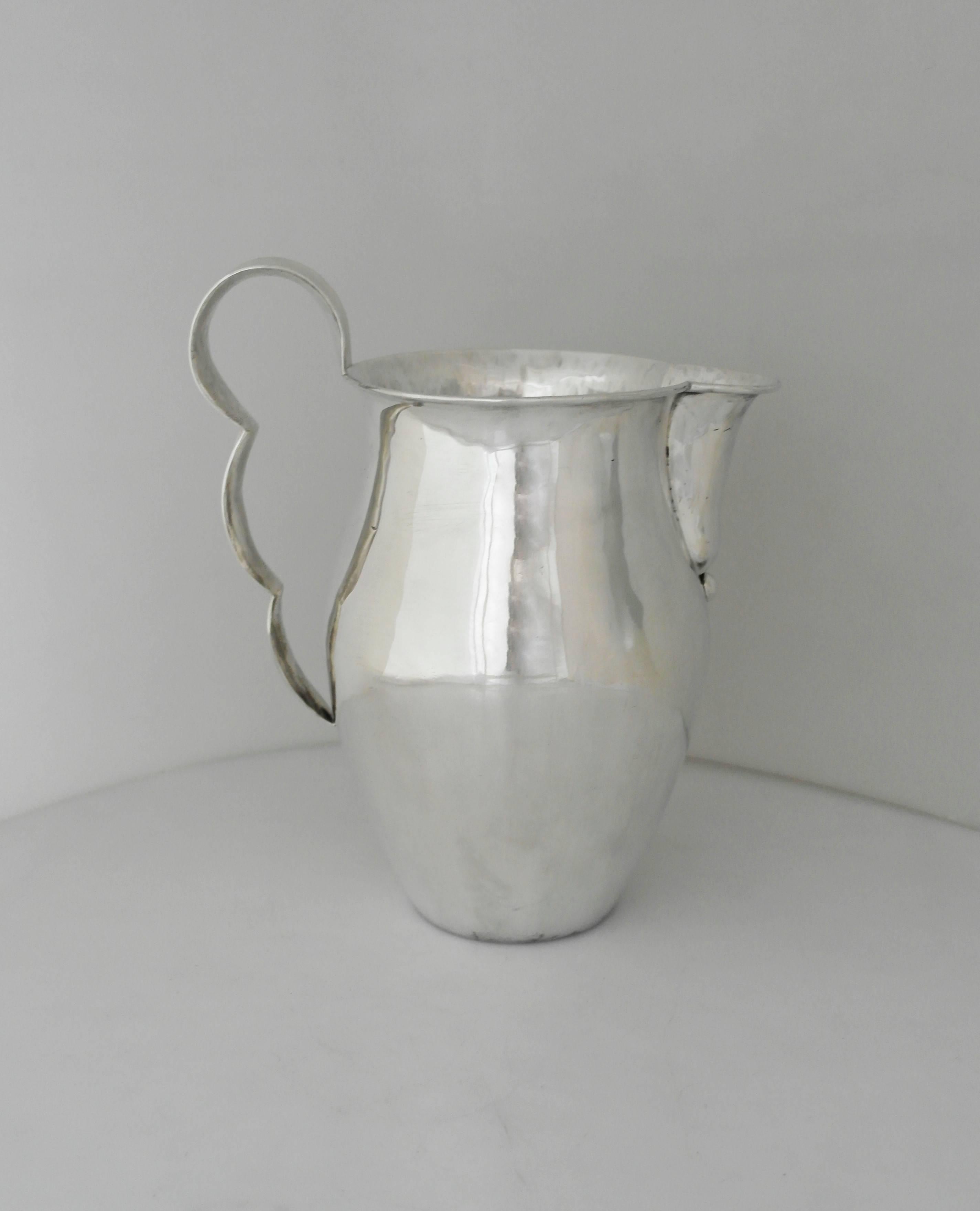 Being offered is a sterling silver pitcher by William Spratling of Taxco, Mexico. Entirely hand-wrought object made during his first design period (1931-1946). Bulbous form with a rolled rim and shaped lip; curved strap handle. Dimensions: 10 inches