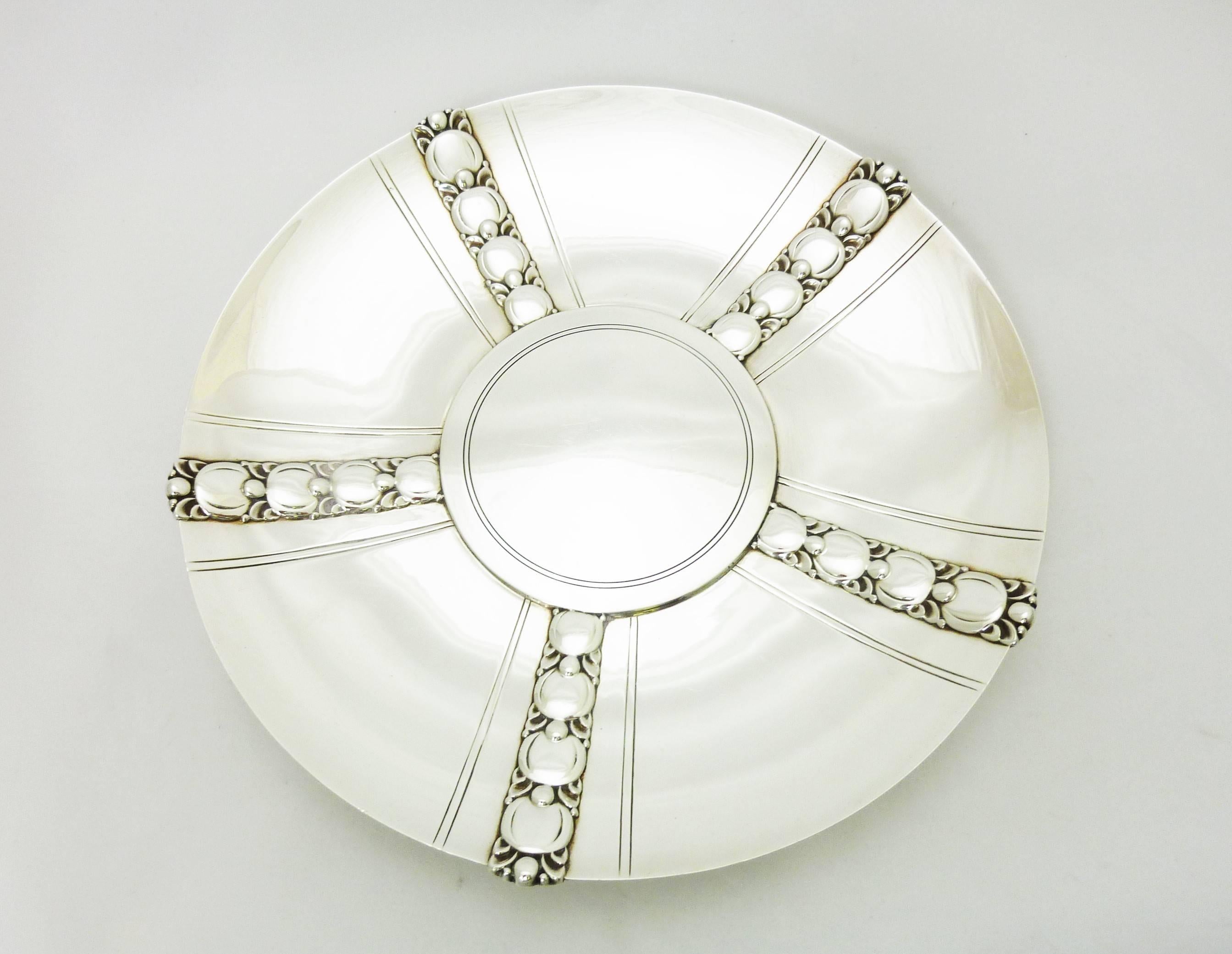 Being offered is a circa 1945 salad serving set by Tiffany & Co. of New York, comprising a bowl, underplate and pair of salad servers in the 'Tomato' pattern. Special pattern designed in 1937 by Olaf Wilford. Dimensions: Plate 10 inches diameter;