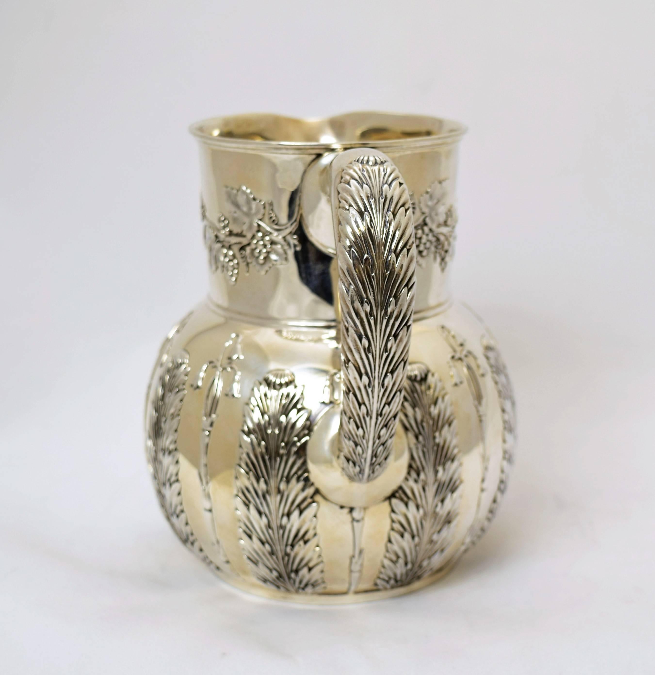 Being offered is a circa 1885 sterling silver water pitcher by Tiffany & Co. of New York, comprising a bulbous form body with applied foliate. It holds 4 1/2 pints. Dimensions: 7 inches height. Marked as illustrated. In excellent condition.