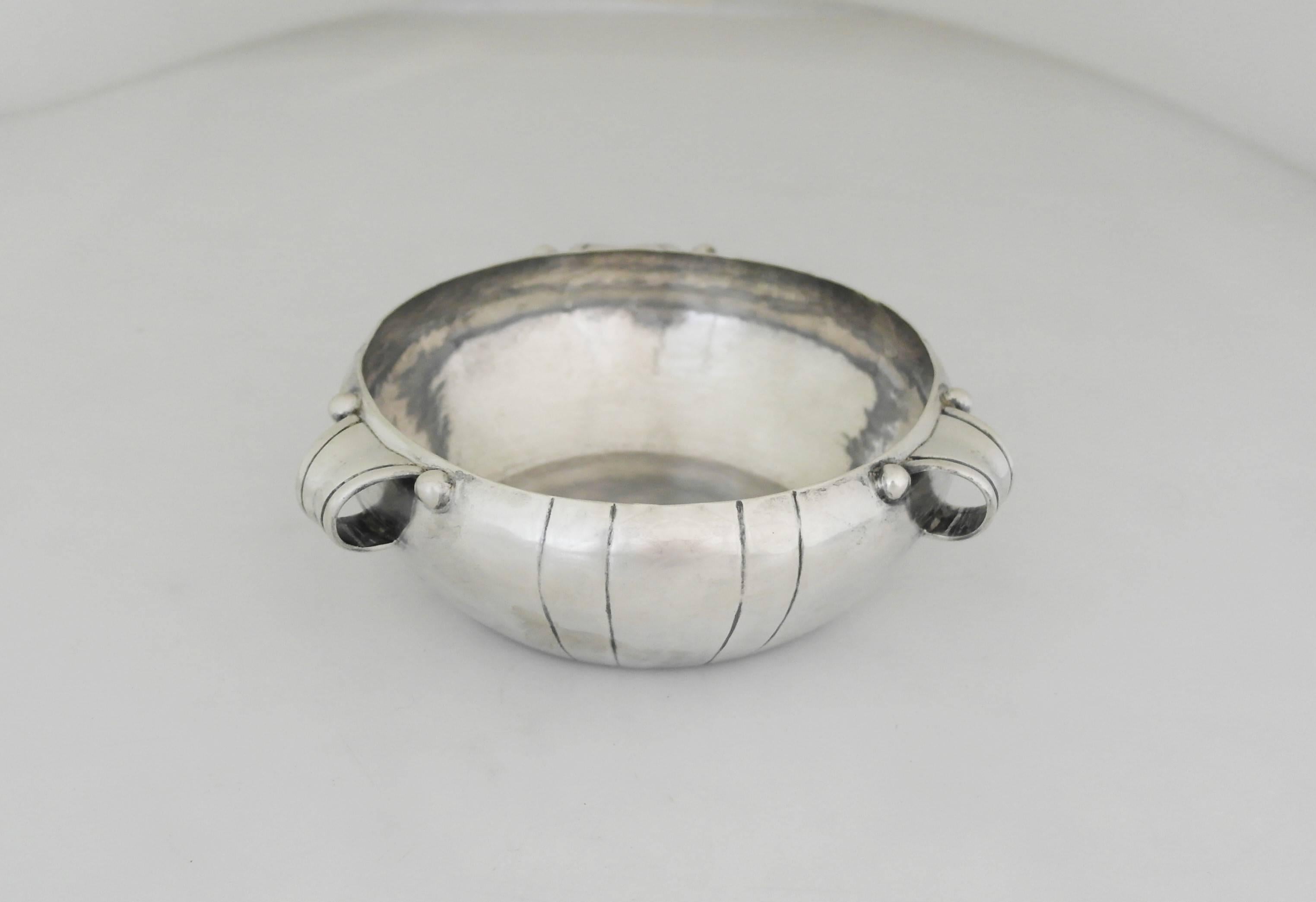 Being offered is an iconic sterling silver bowl by William Spratling of Taxco, Mexico, made during his first design period (1931-1946), entirely handmade with three looped handles and vertical incised lines as the primary decorative element.