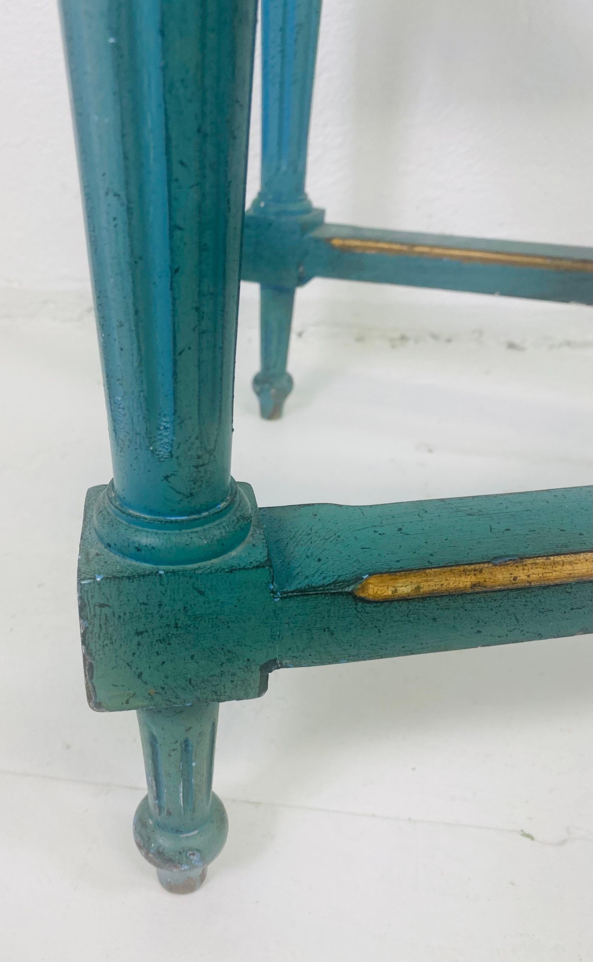Se trata de una mesa de centro pintada a mano de estilo Imperio francés de mediados del siglo XX. Esta mesa de centro está pintada a mano en tonos azul francés y dorado. La mesa tiene una pata imperio que llega hasta un penacho de plumas tallado en