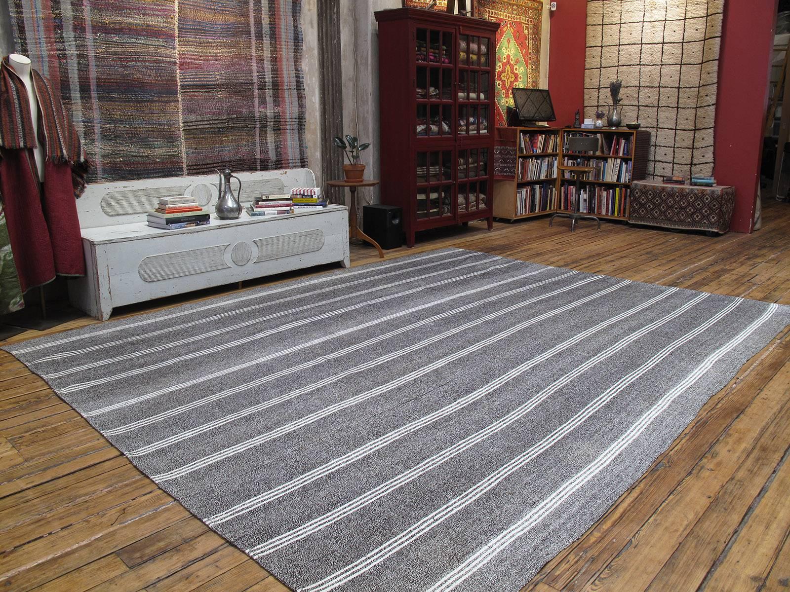 Kilim rug with vertical stripes in white cotton. A simple old tribal flat-weave rug from South-Eastern Turkey, woven with an ingenious mixture of goat hair and cotton, originally used as an everyday floor cover or in the fields during harvest time.