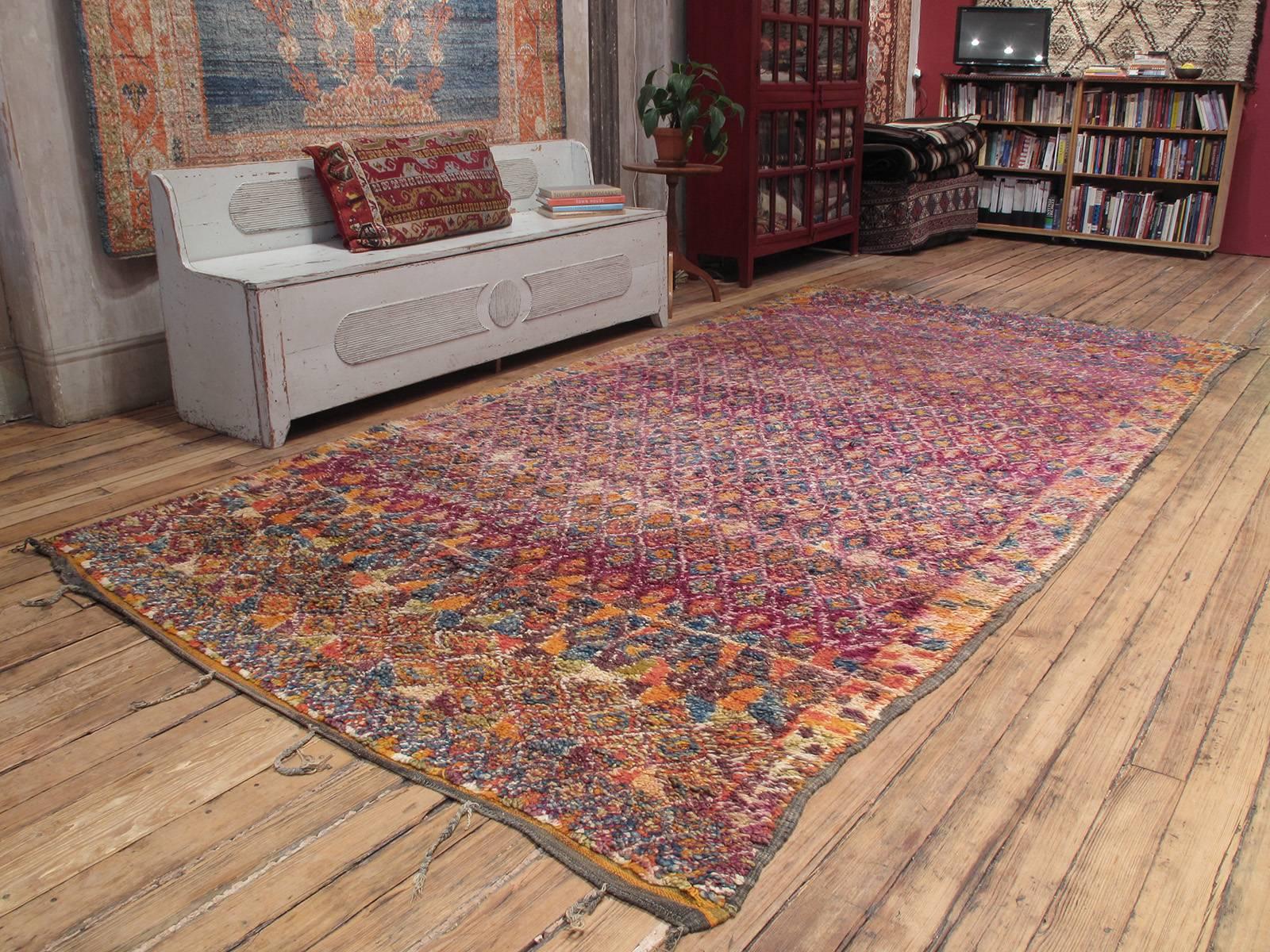 A great old Berber carpet from Morocco, woven by the Beni Mguild tribes of the Middle Atlas Mountains. An interesting example featuring a somewhat unusual design type in richly saturated tones of purple, blue and orange. A very large, heavy and