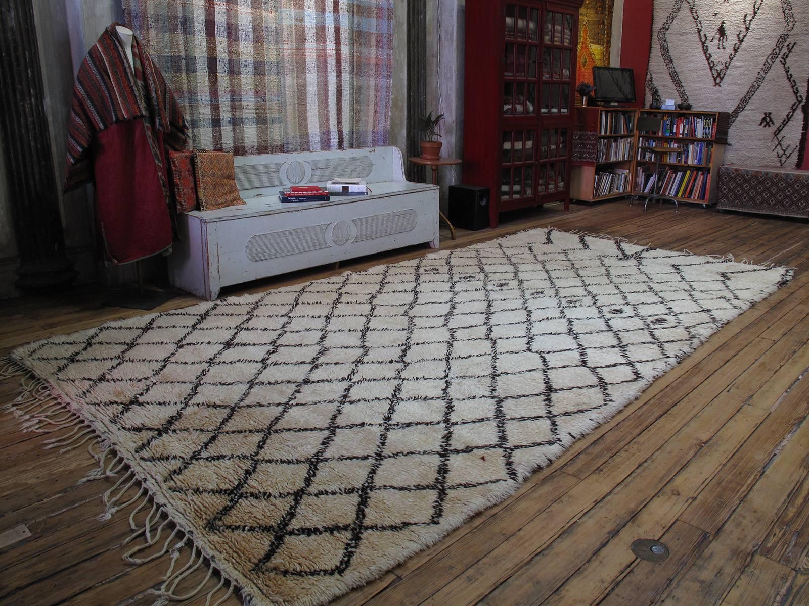 A massive Moroccan Berber carpet by the Beni Ouarain tribes of the NE Middle Atlas Mountains. The classical diamond grid, executed in small scale is dramatically interrupted at the top. A heavy, sturdy piece that was originally used as a comfortable