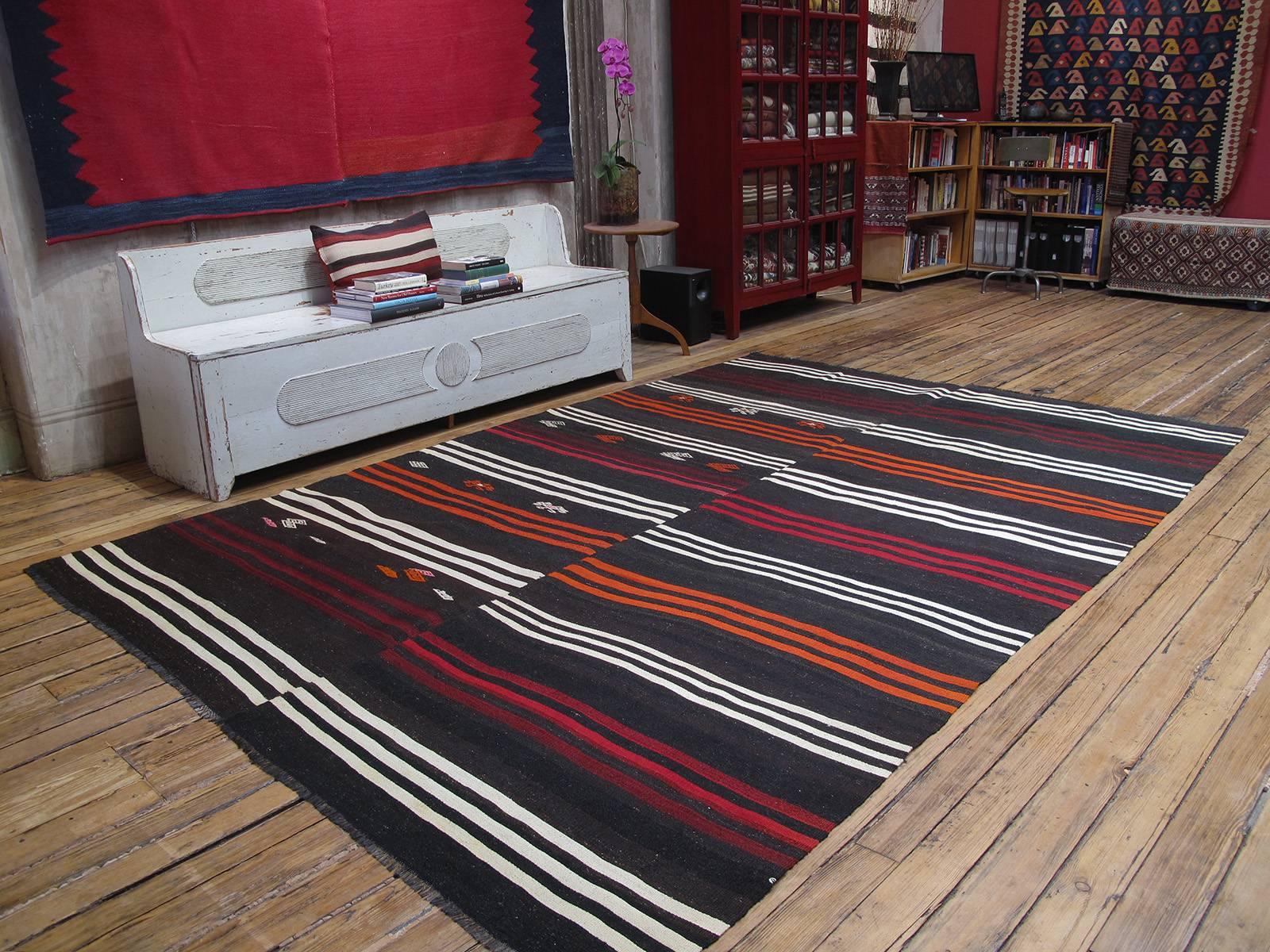 Striped goat hair Kilim rug. A large tribal floor cover or rug from Southeastern Turkey, woven in two panels on a narrow home loom. It is a rough, heavy and Primitive piece with dark brown goat hair and brightly colored stripes and scattered tribal