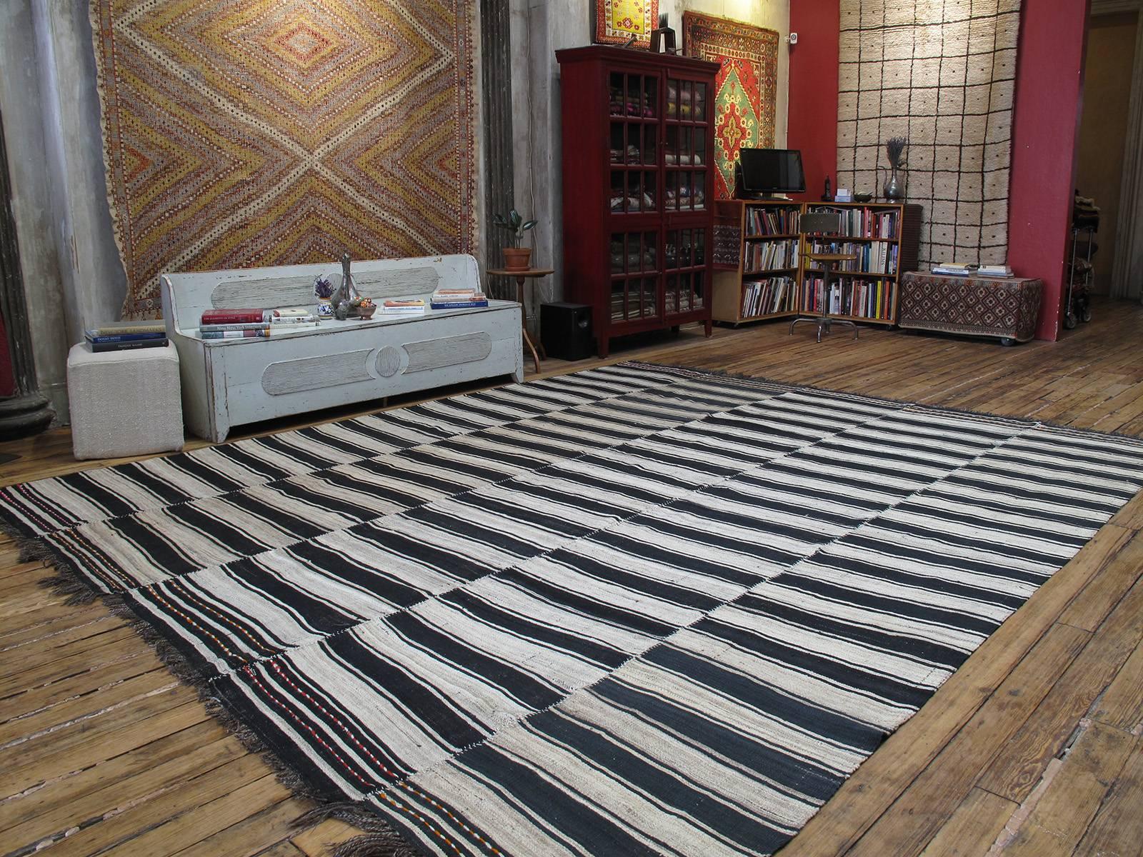 This large tribal Kilim from Northern Iran was woven in five narrow panels on a narrow loom, with alternating bands of black-brown and ivory. Note the pleasing tonal variations in the close-up photos, lending depth and character to this authentic