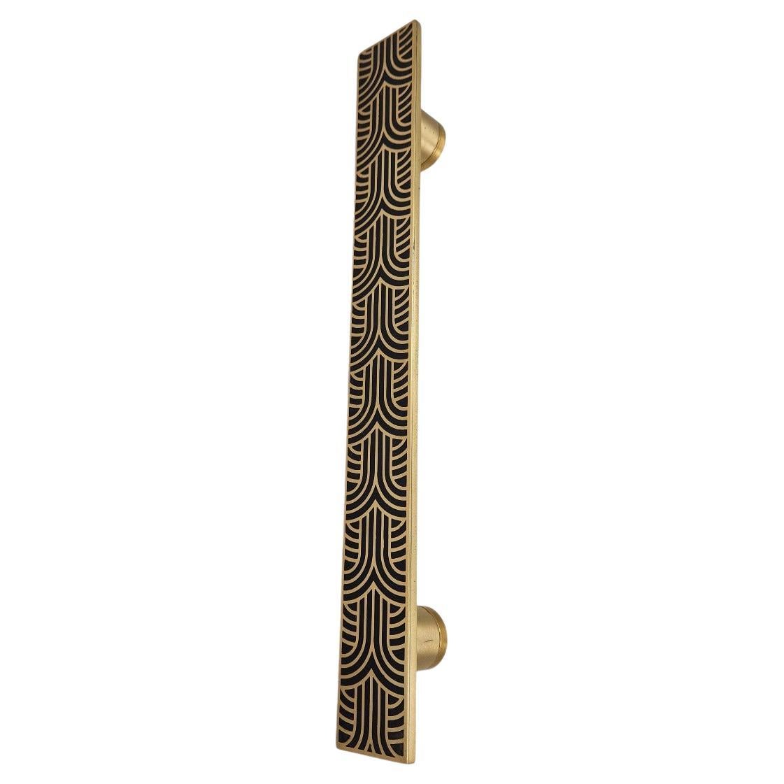 The PT/AD/10/30 cm cabinet pull, handcrafted in engraved brass, showcases a finely executed geometric pattern, creating a refined textured effect. Its aged gold and black finish enhances the depth of the brass, interacting with light to emphasize