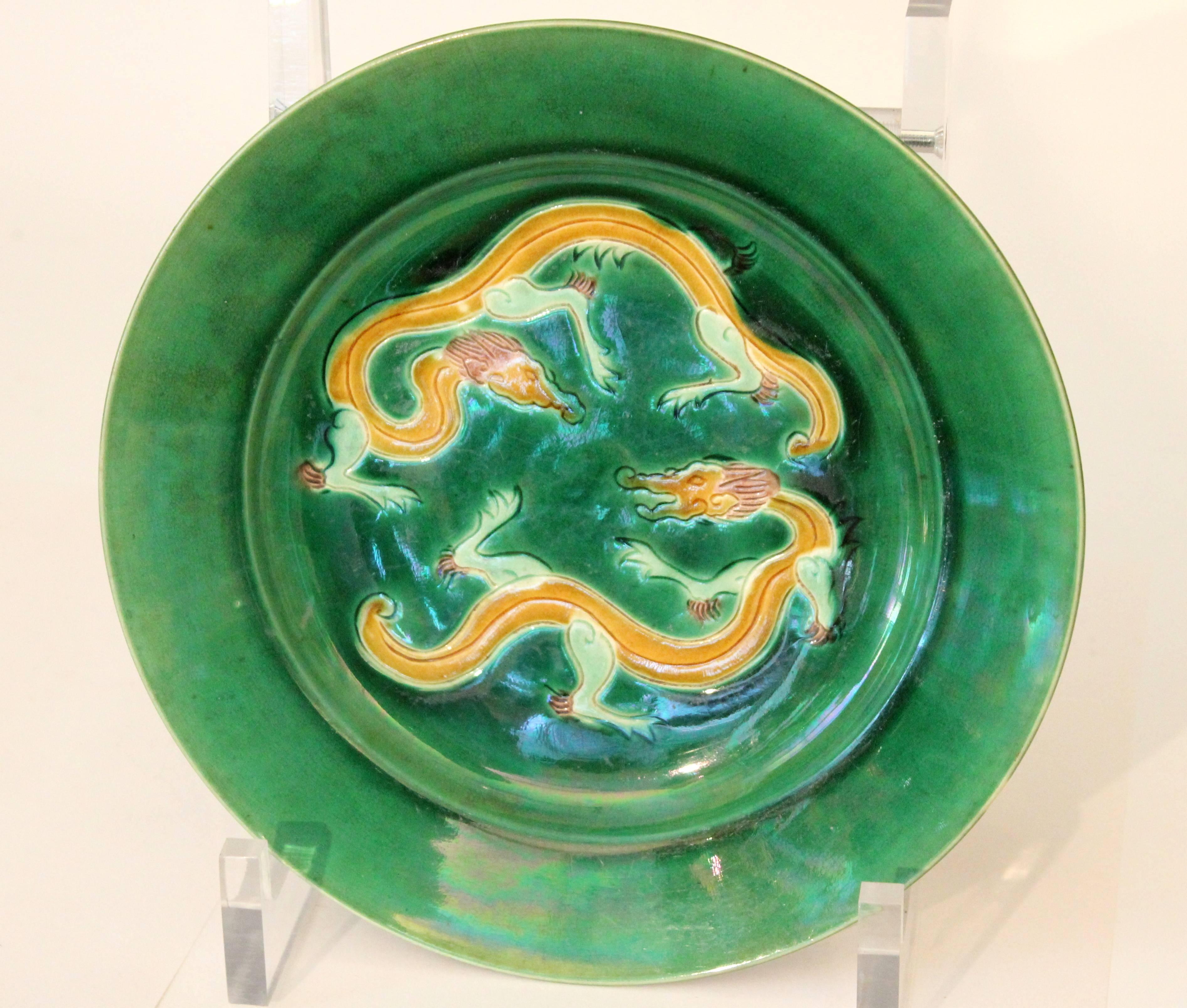 Antique Awaji Pottery plate with opposing dragons on a deep green ground. Three color (sancai) glaze in emulation of the Chinese style, circa 1880s. From the original kiln started by Kashu Mimpei. Impressed plover mark on base. 8 5/8