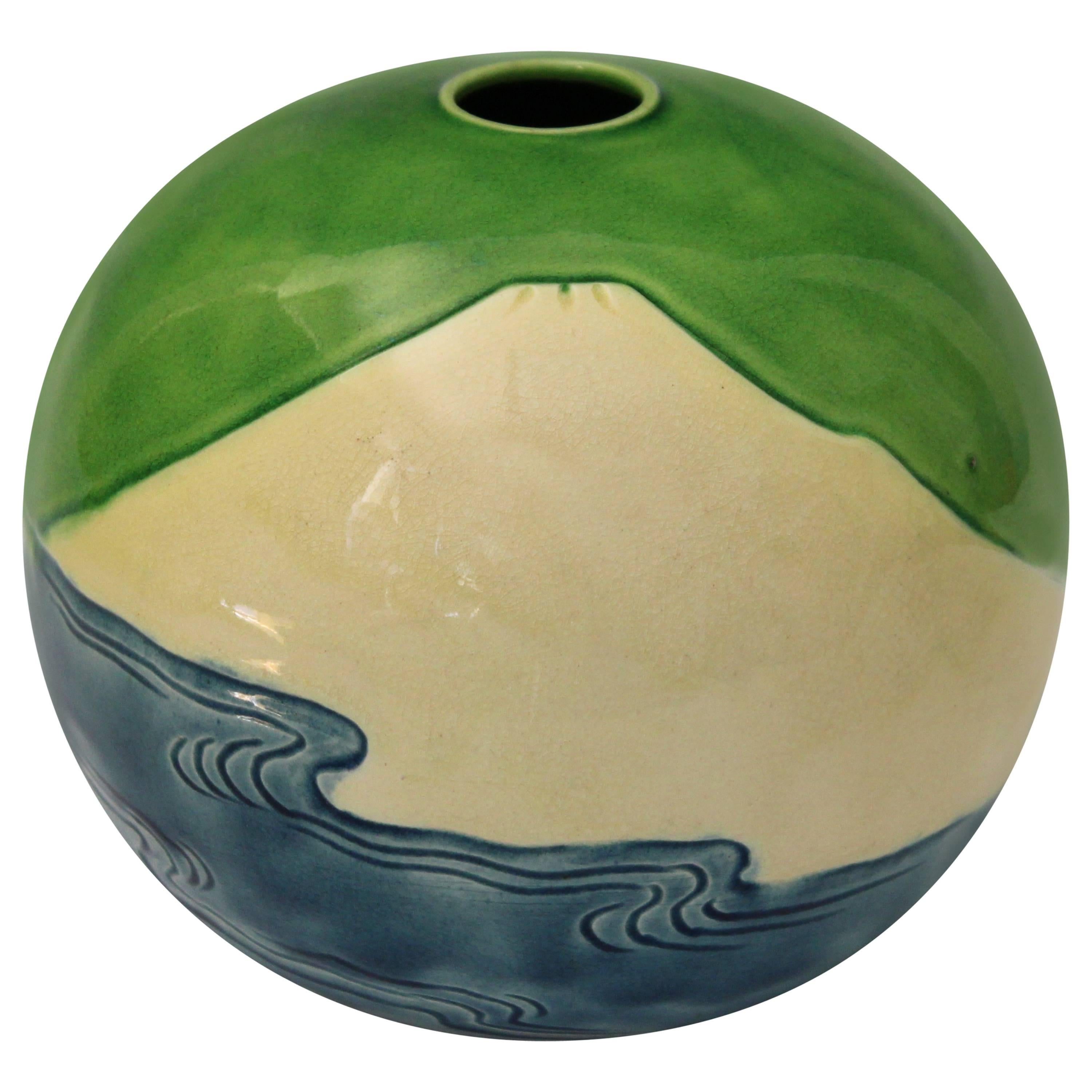 Spherical vase with incised image of a mountain above the ocean against a vibrant lime green sky. Impressed Kiln mark. Measures: 5