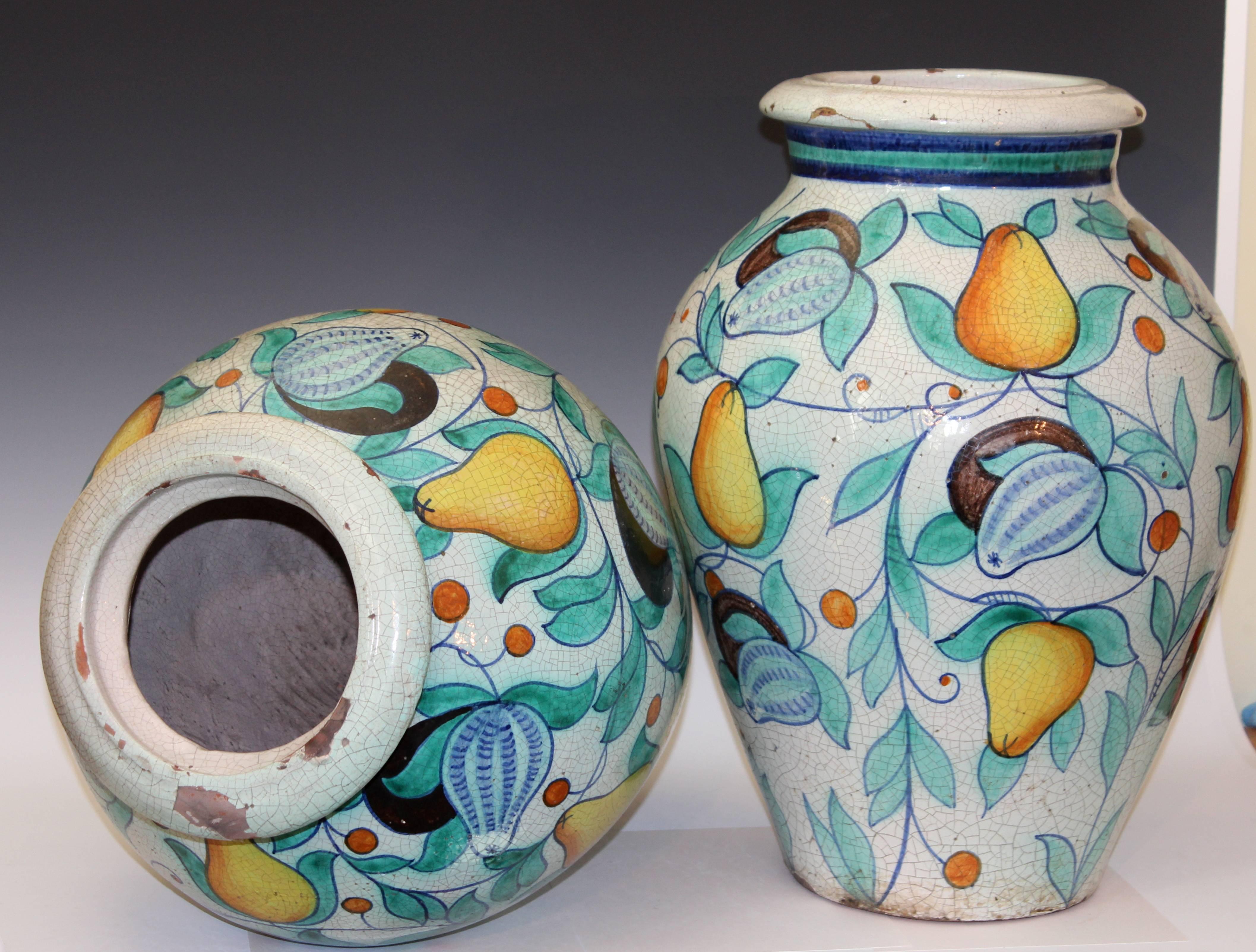 Large pair of old Deruta Italian faience pottery jars, circa early/mid 20th century. Painted in bright enamels with lyrical scrolls of pears and pomegranates on a crackled tin glaze ground.  22