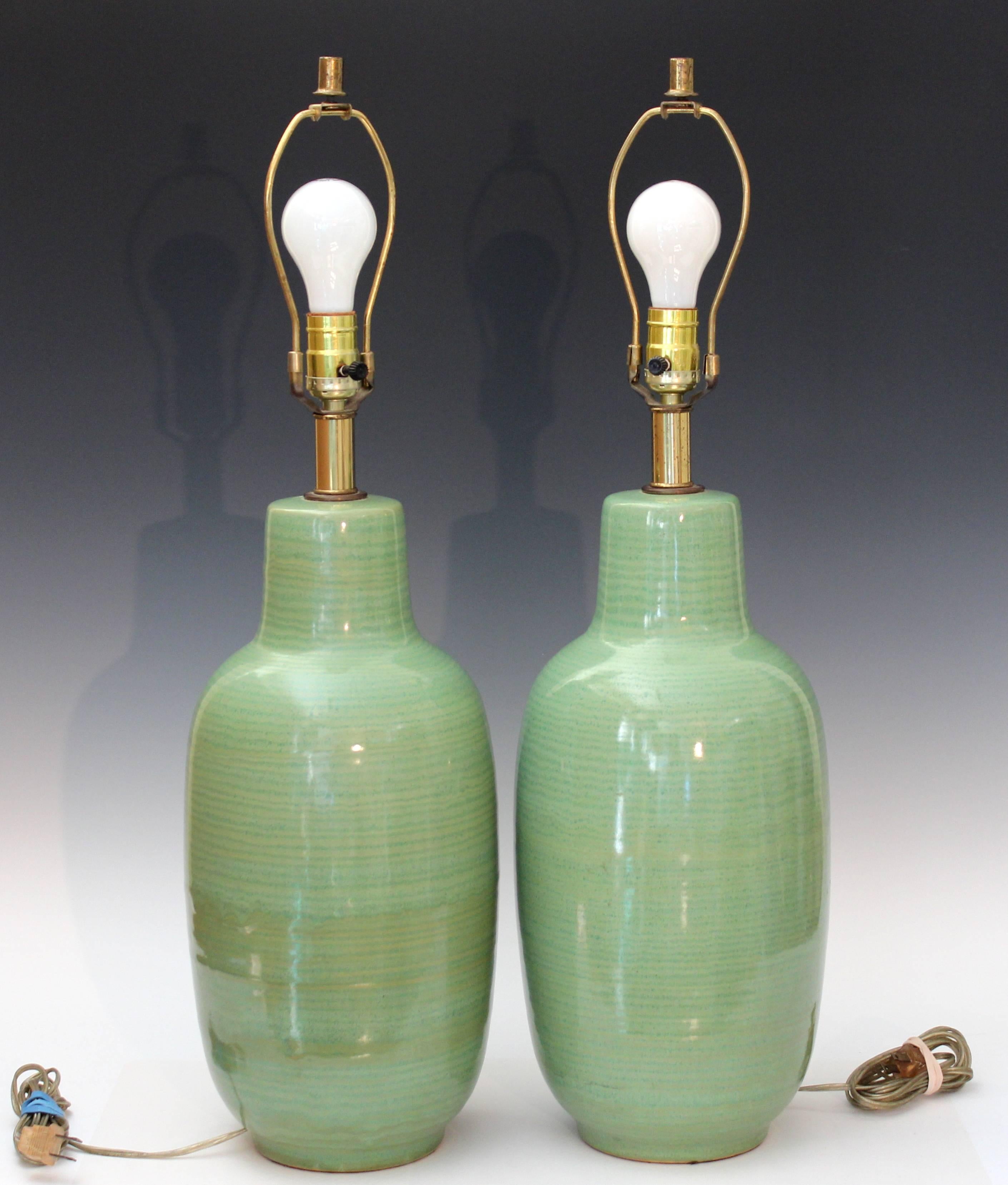 Large vintage Studio Pottery lamps with alternating bands of light and dark celadon green glaze, circa 1960s. Nice quality with good weight for stability. Measures: 28