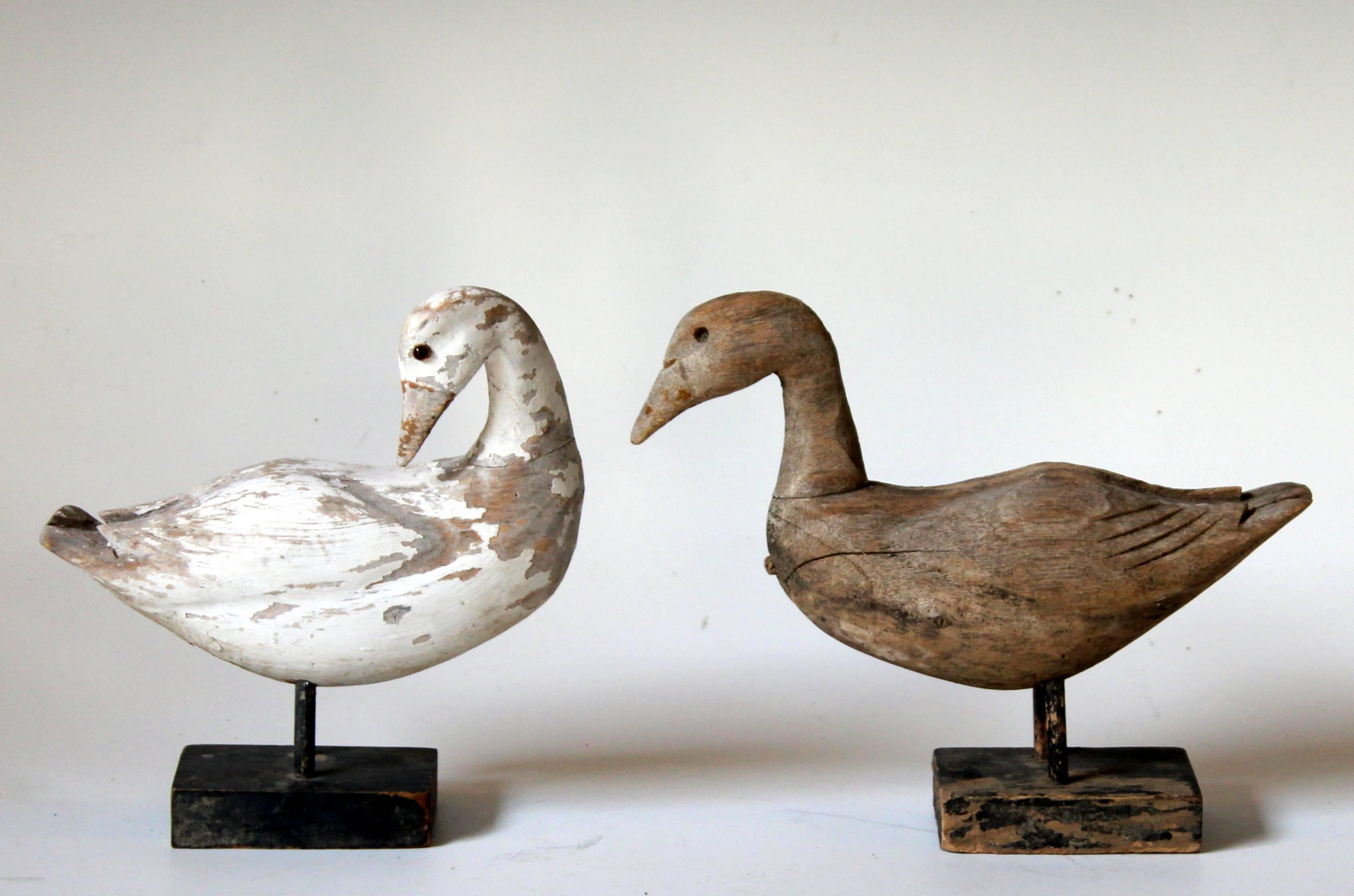Pair of old vintage carved painted wood duck figures on stands. One retaining glass eyes and most of painted finish, the other missing eyes and with finish worn away. Charming and whimsical folk art pair. Each 6 3/4