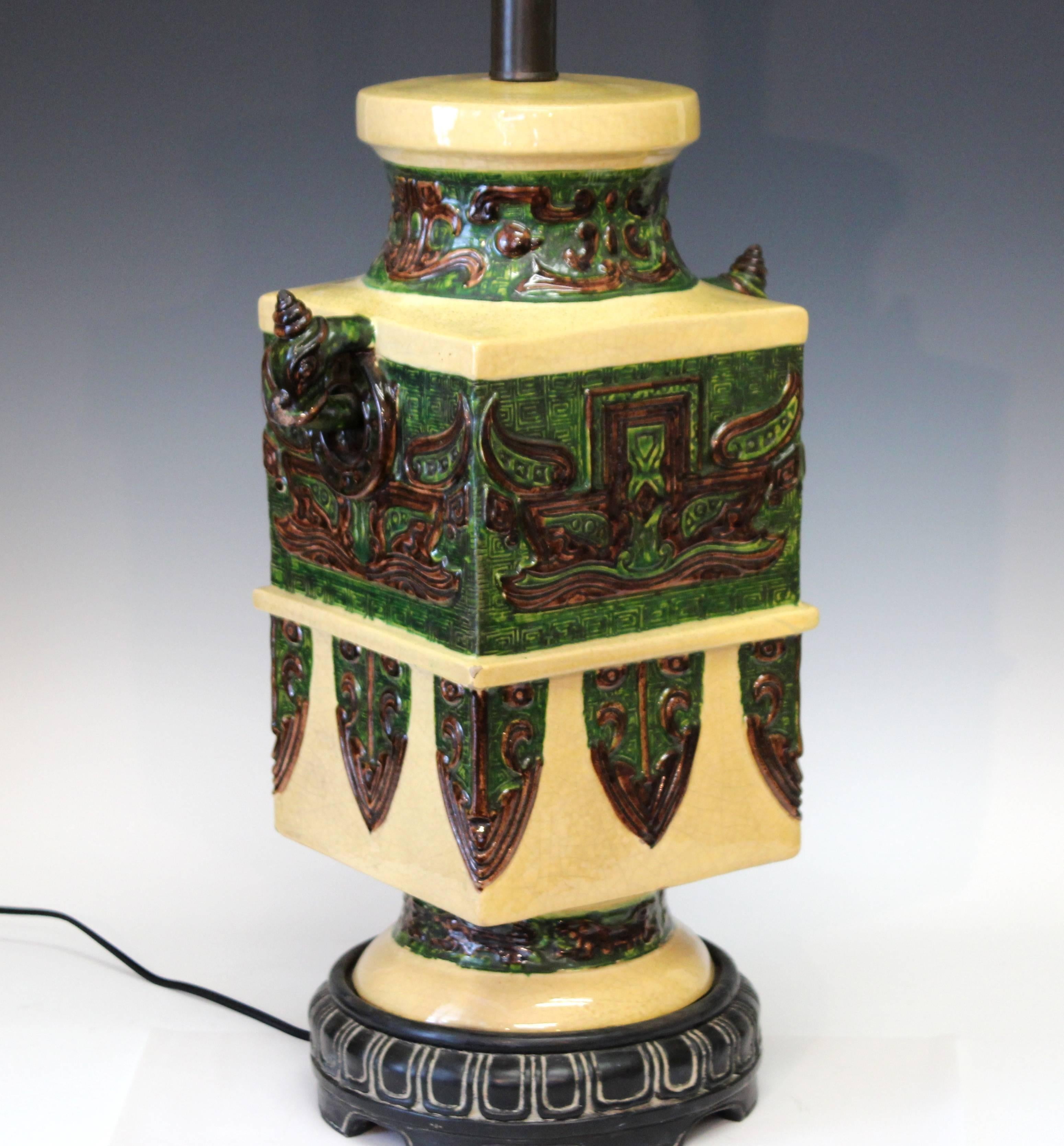 Large and heavy Zaccagnini Mid-Century Ming table lamp modeled after an antique Chinese bronze vase with taotie masks, ceremonial blades and ring handles. Separate pottery base glazed to look like carved wood. 38" high overall. Excellent