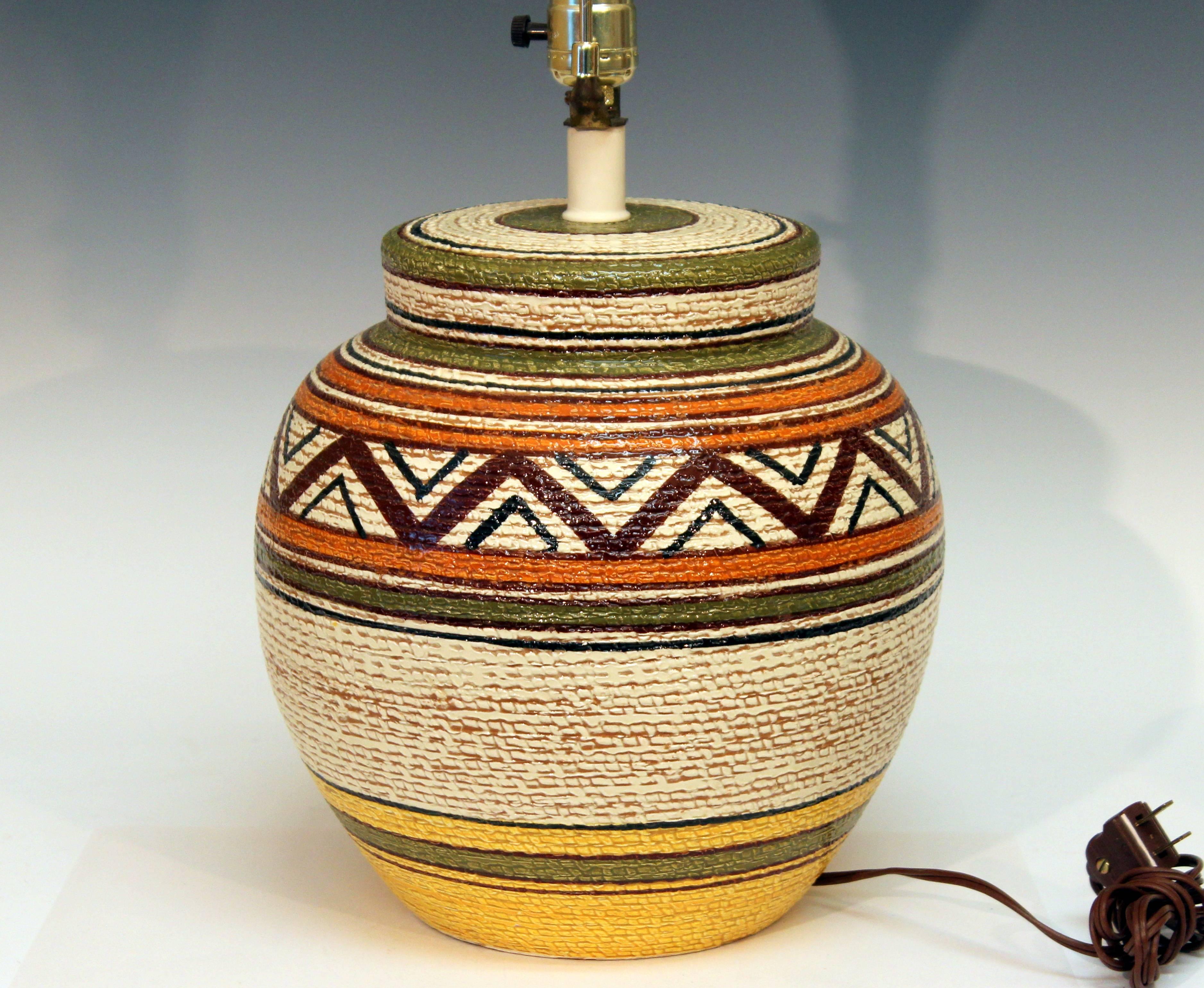 Big, heavy, hand-turned, vintage Bitossi lamp with earth colored glazes in geometric pattern over a basket weave ground, circa 1970. Measures: 23" high overall, 13" to base of socket, pottery only is 11" high, 11" diameter. Shade