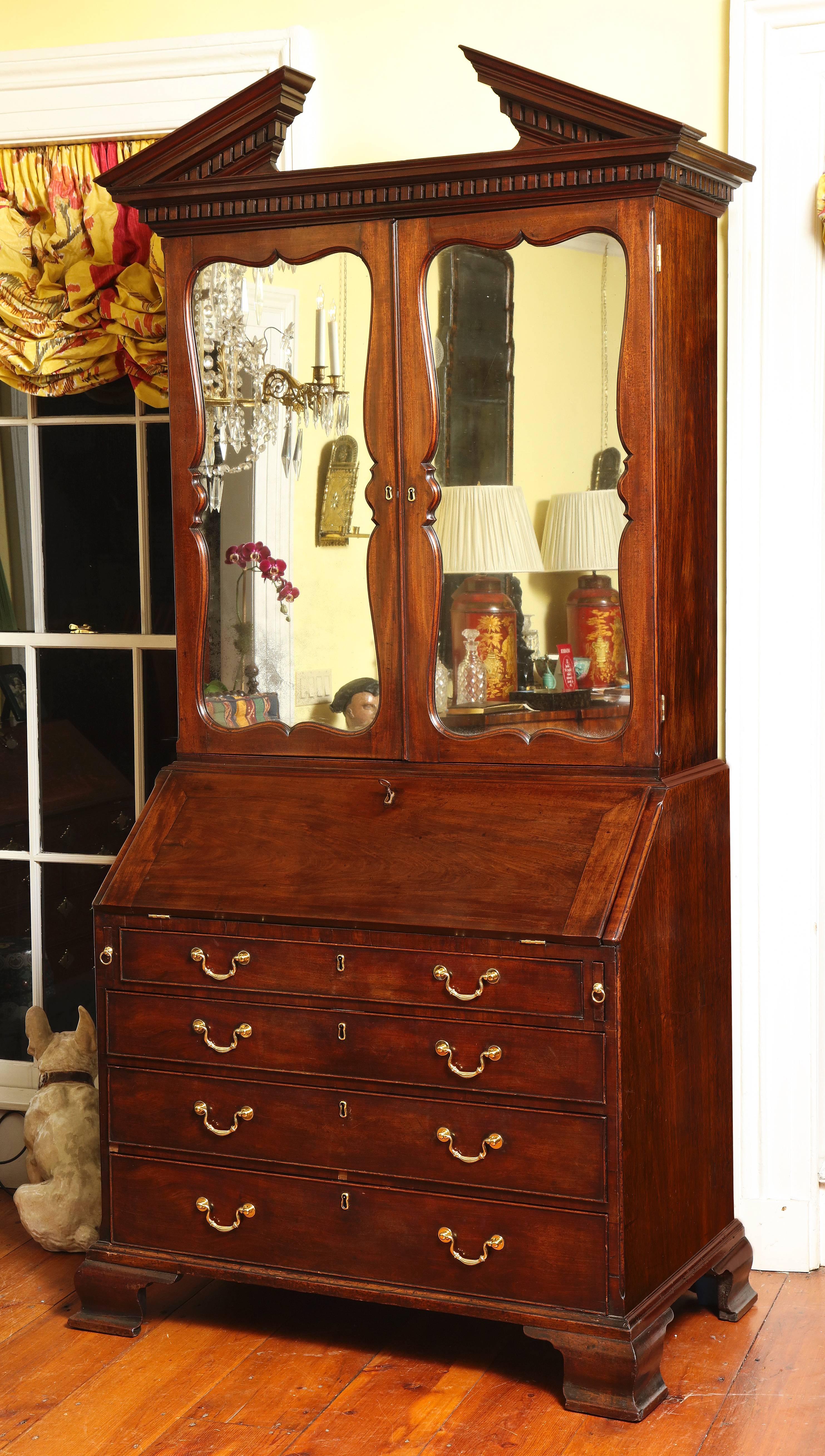Very Fine George II Mahogany Bureau Bookcase, attributed to Giles Grendey, having a broken pediment with carved dentils above two cartouche shaped mirror doors retaining the original mirrors, and having a slant front fitted desk section above four