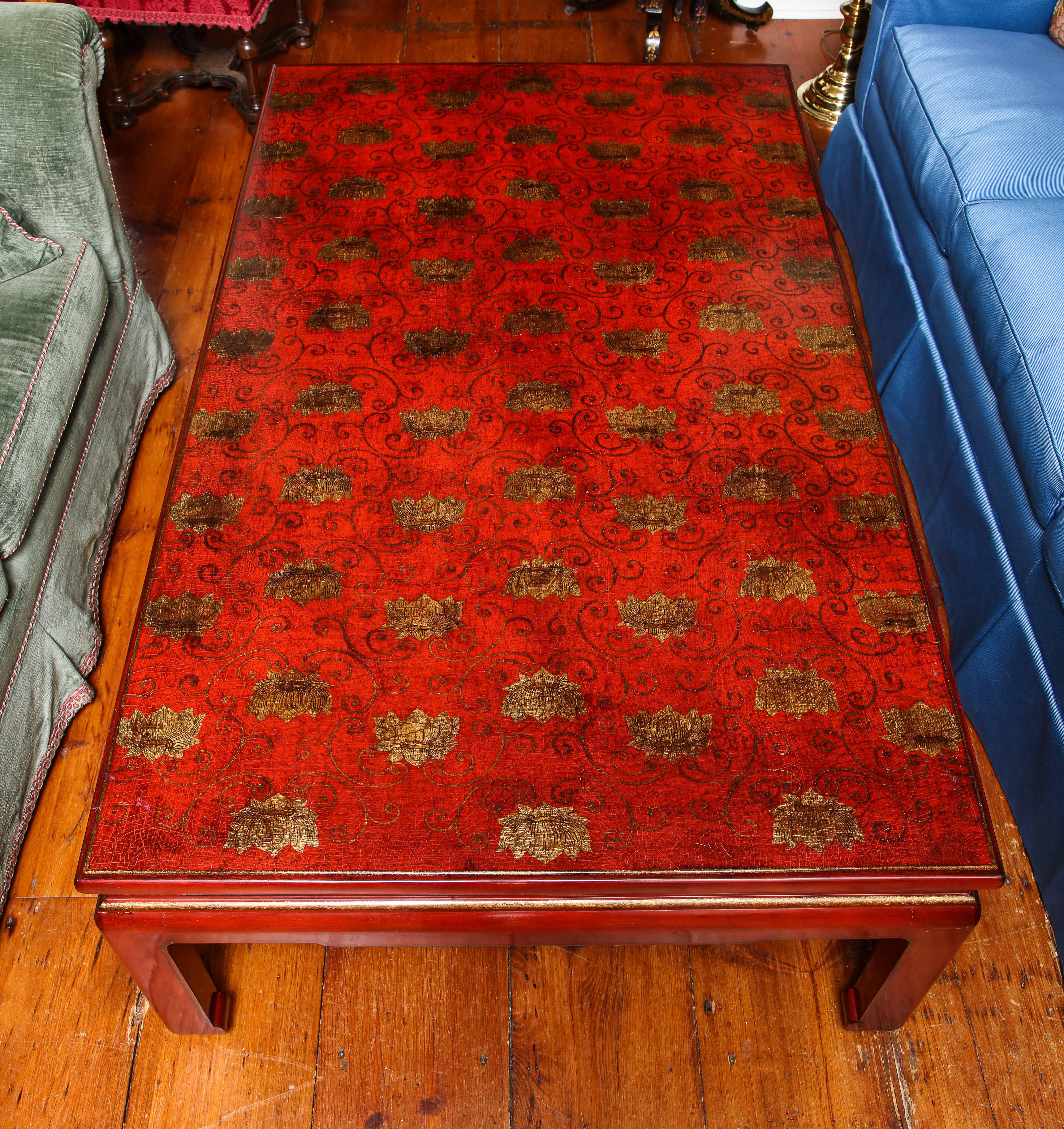 Fine red lacquer rectangular coffee table the top having finely decorated gilt scrolls and lotus blossoms, above a recessed apron with horizontal cut-outs on square cut straight Chinese style legs with scroll foot. Made in Paris, 20th century.
