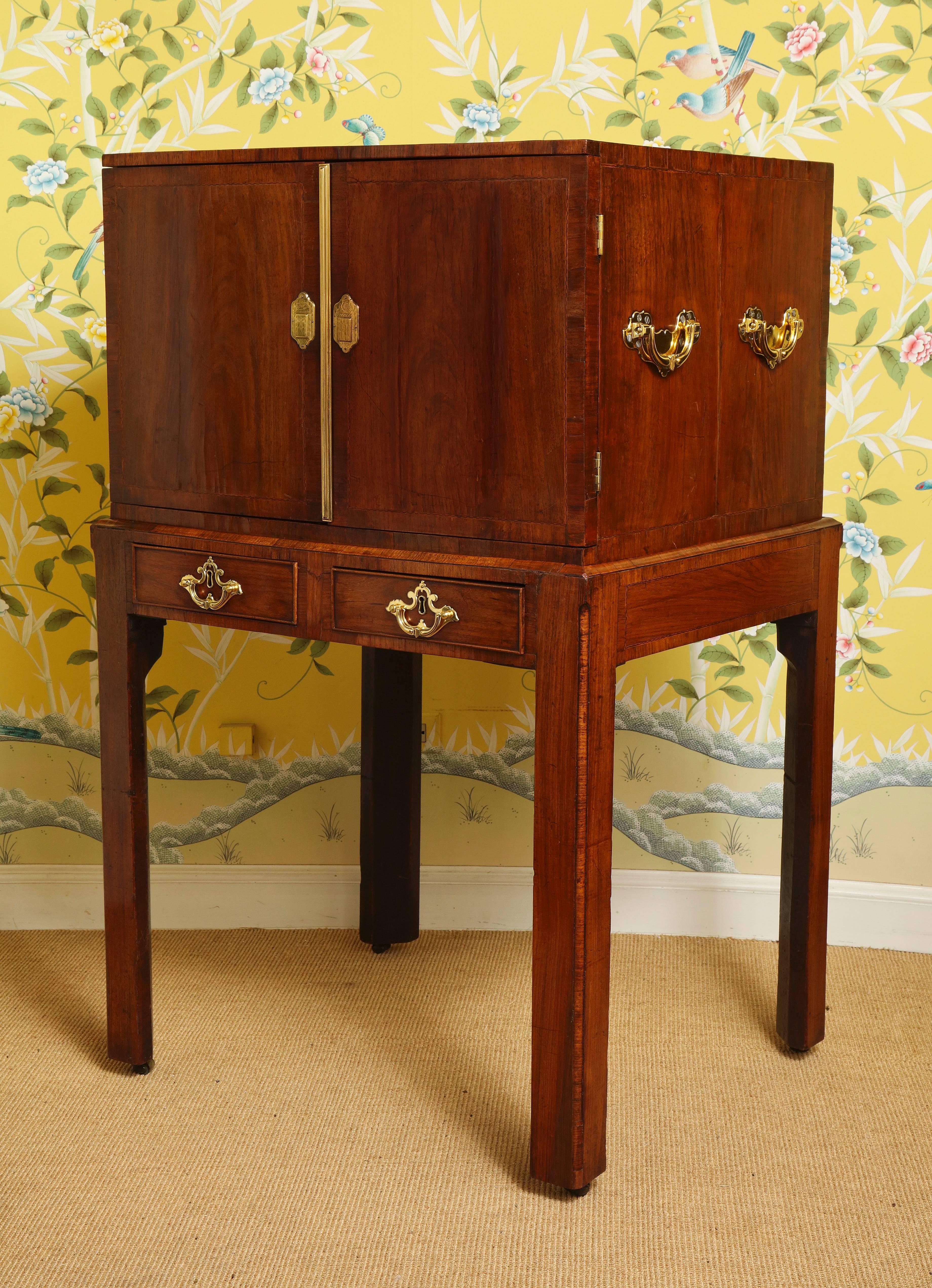 Very fine George II Padouk and walnut cabinet on stand, the cabinet is unusual in that it is finished on all four sides with finely book matched veneers inlaid with checkering and crossbanding. The cabinet with a pair of doors veneered on both sides