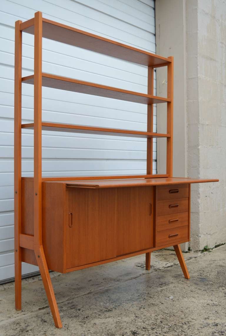 Teak credenza with pull-out desktop with adjustable upper shelves. Lower section has sliding cabinet doors with two interior shelves and four ample exterior drawers. Handsome sleek style. 


Additional dimensions: 
16.5