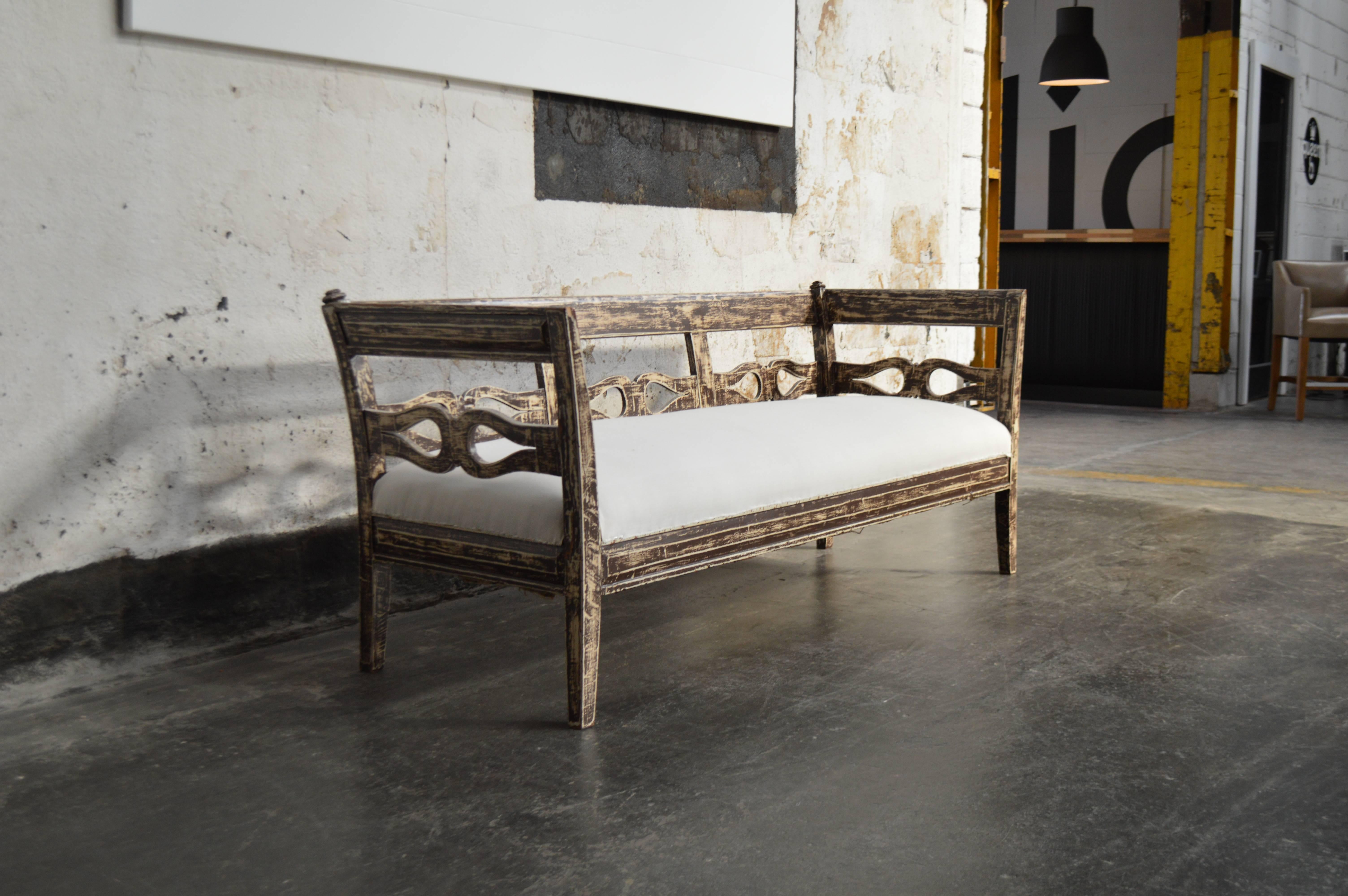 Restored Swedish Country settee, sofa or bench in the Gustavian Style. Probably late 19th century, but possibly earlier. 

 The top layer of brown paint has been partially distressed to reveal the original white paint color. All wood has been