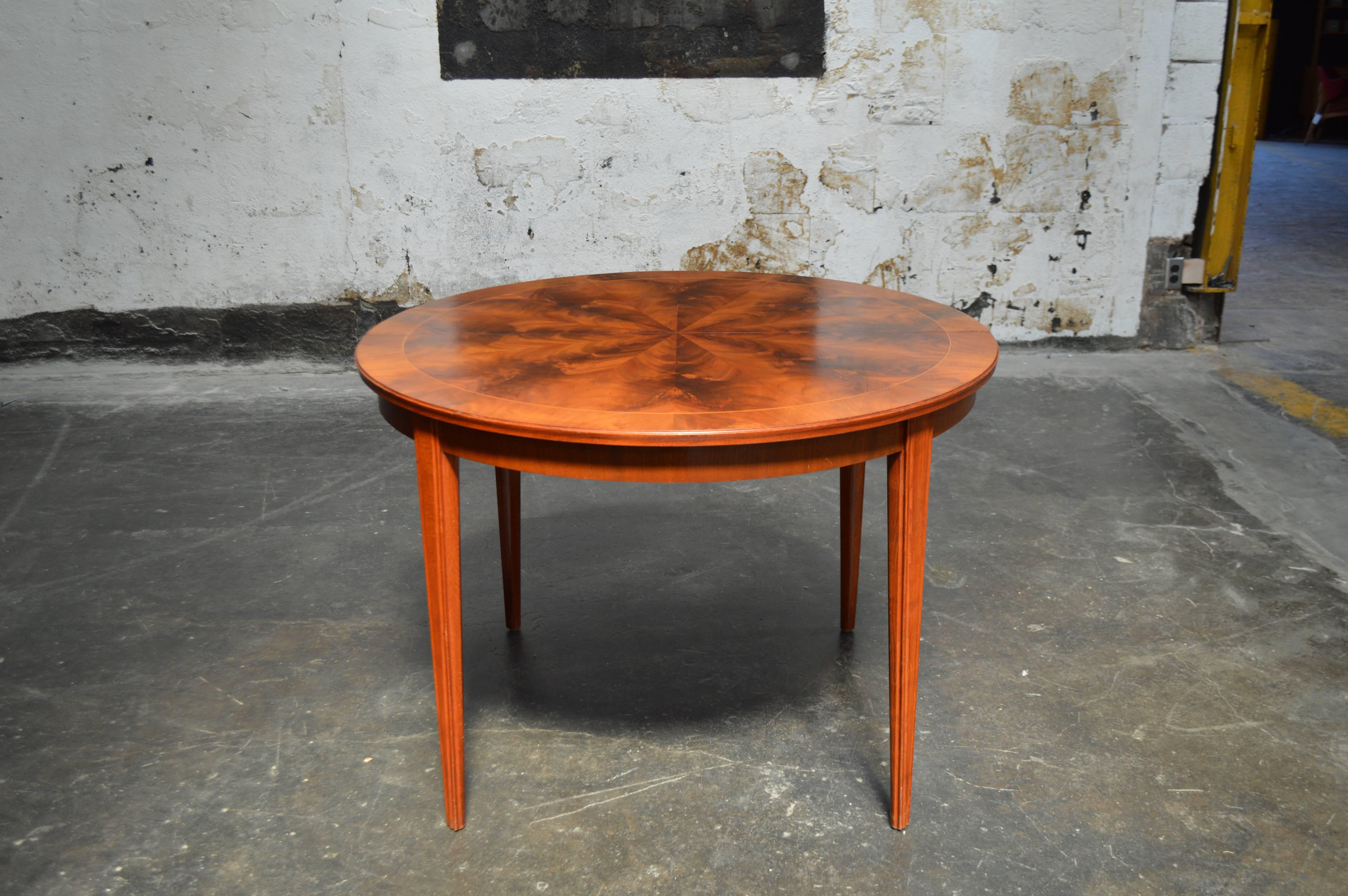 Handsome round mahogany Svenska Mobler dining table with bookmatched top and intarsia trim. Originally made to have a leaf but that piece is long gone so it has been connected on the bottom to keep in place. Sturdy tapered legs finish off this piece