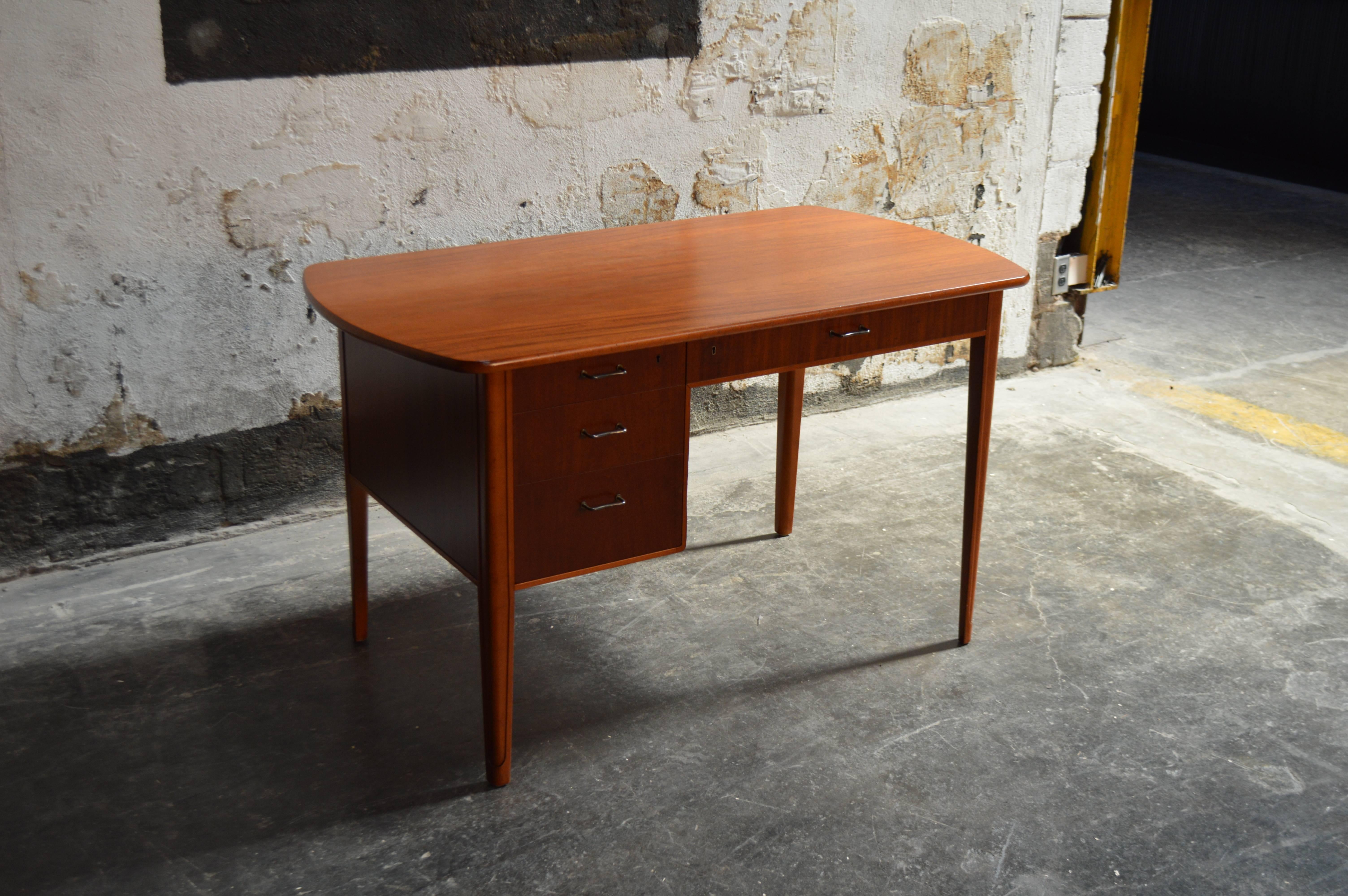 Handsome Swedish Art Moderne desk. Made of mahogany. Ample storage space detailed with brass pulls atop streamlined tapered legs. Finished on all sides and lockable drawers.