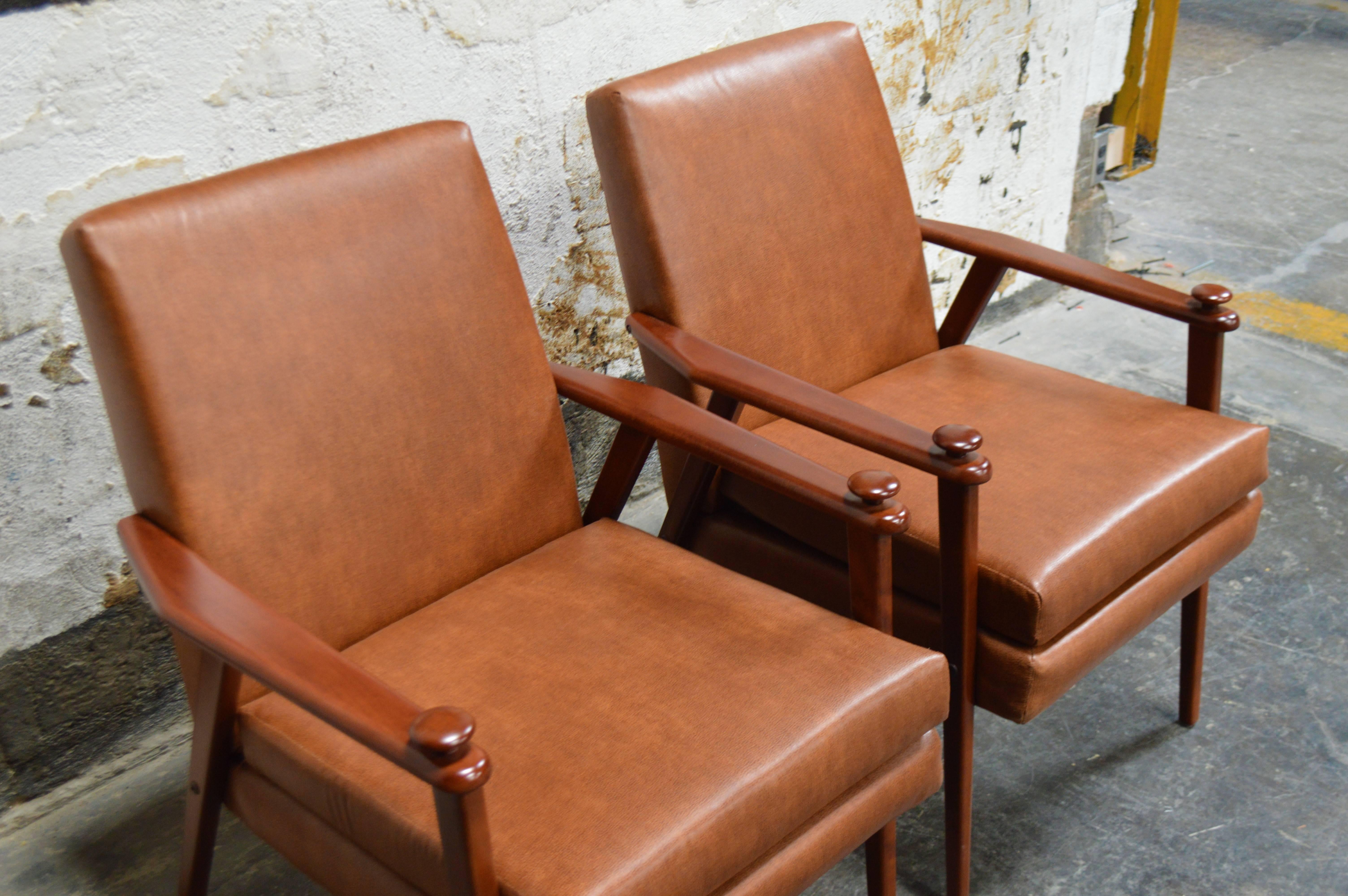 Mid-Century lounge armchairs, circa 1950s. Teak framework and detailed with knobs on the arms. Originally two separate but similar chairs that we have refinished, refined and reupholstered to match. Recently reupholstered in durable recycled leather