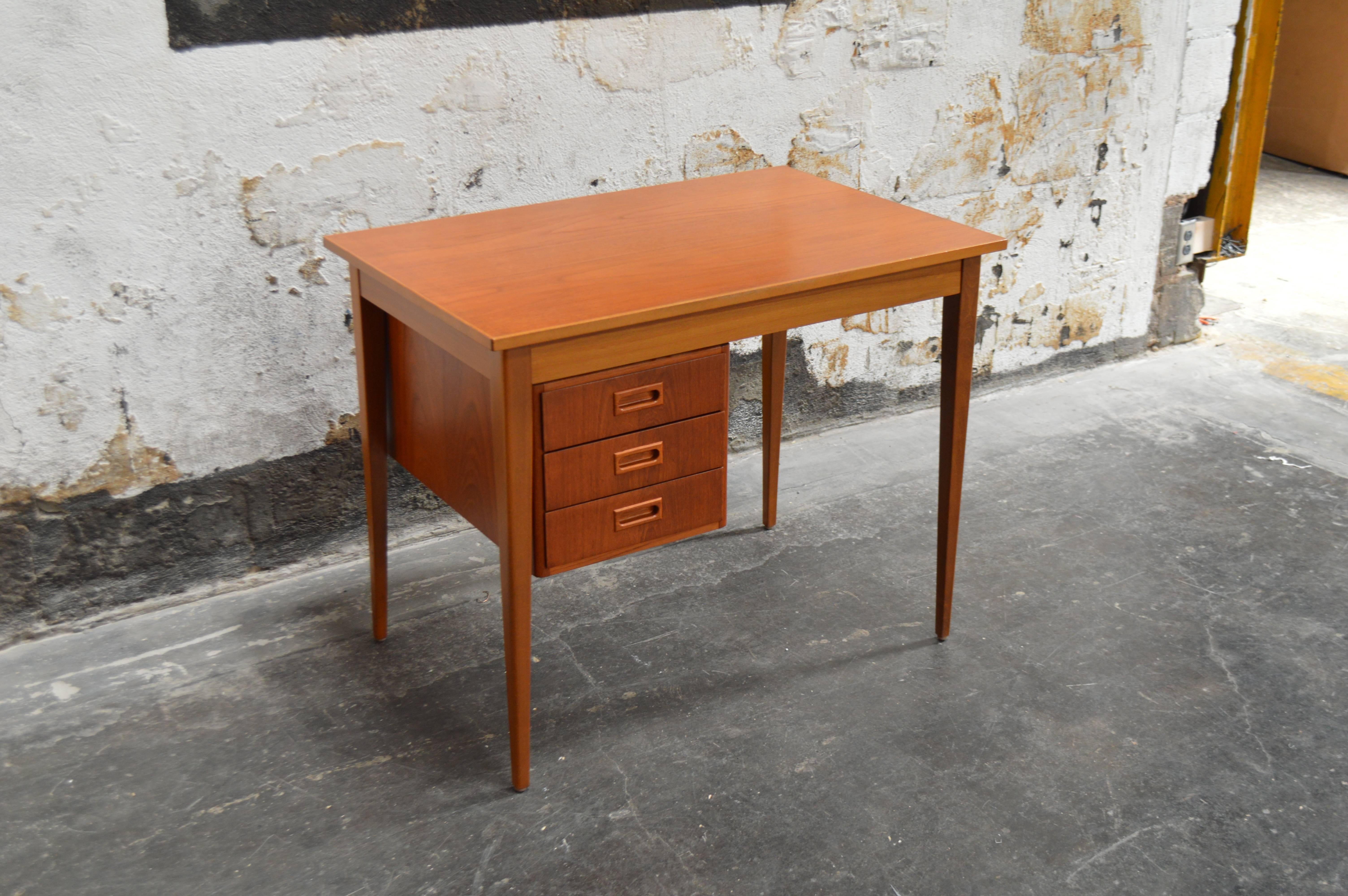 Handsome Mid-Century teak desk in the manner of Arne Vodder. Three drawers that easily slide from side to side sitting atop nicely tapered legs.