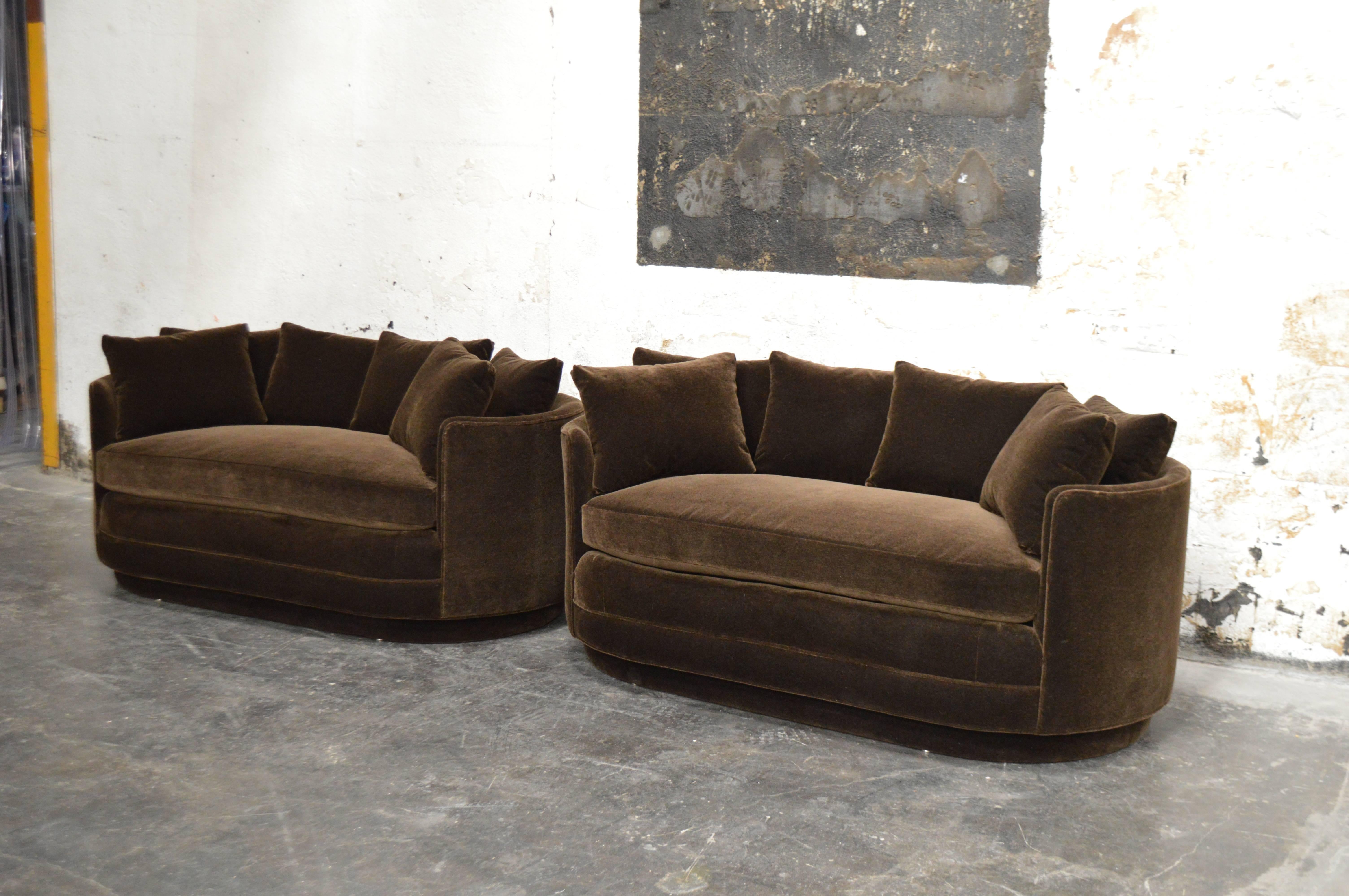 Handsome tailored pair of curved loveseat sofas newly restored and upholstered in a luxurious chocolate brown mohair. Curved pill shape form cozy small-scale sofas with custom back pillows included. 

Note - Sofas appear richer and darker in
