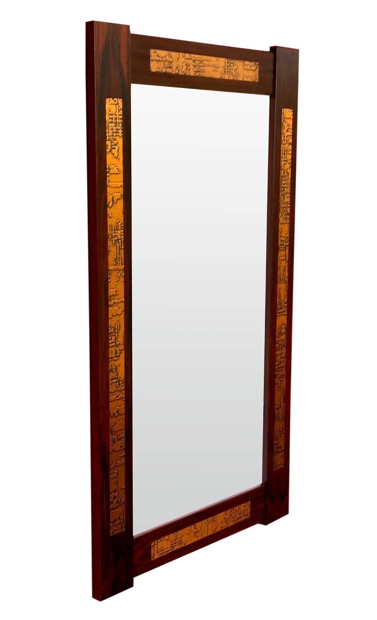 A beautifully crafted 1960s vintage mirror from Pedersen and Hansen. The teak frame has a rich reddish hue and is accented with acid-etched copper inlays in relief. Each inlay has a unique, random pattern.
In excellent vintage condition with minor
