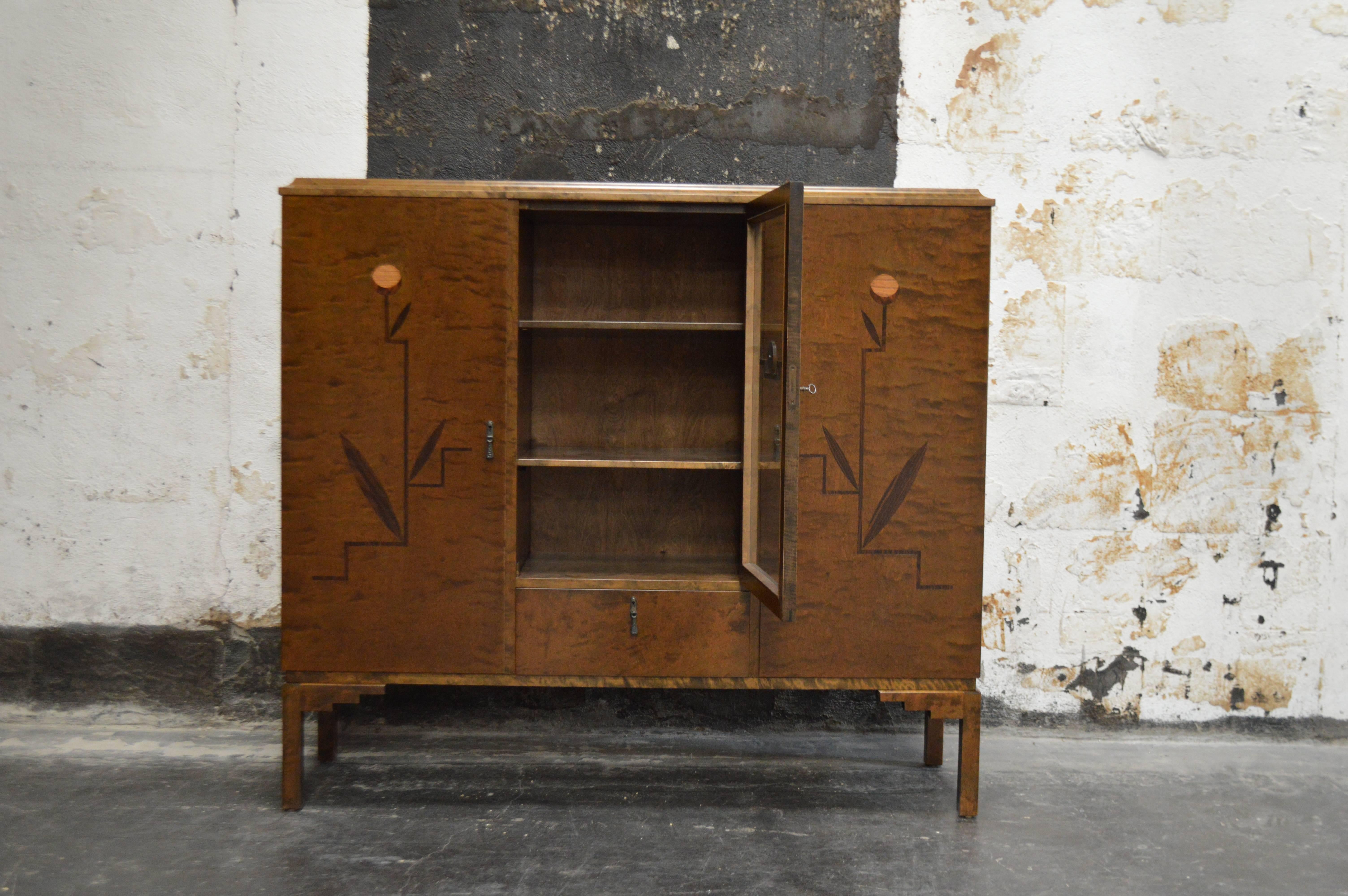 Swedish inlaid Art Deco or neoclassical bookcase or storage cabinet, Sweden, circa 1930s. Exterior dark flame birch. The front two side doors are paneled and inlaid with intarsia of ebonized birch, mahogany, elm and jacaranda wood. The center door