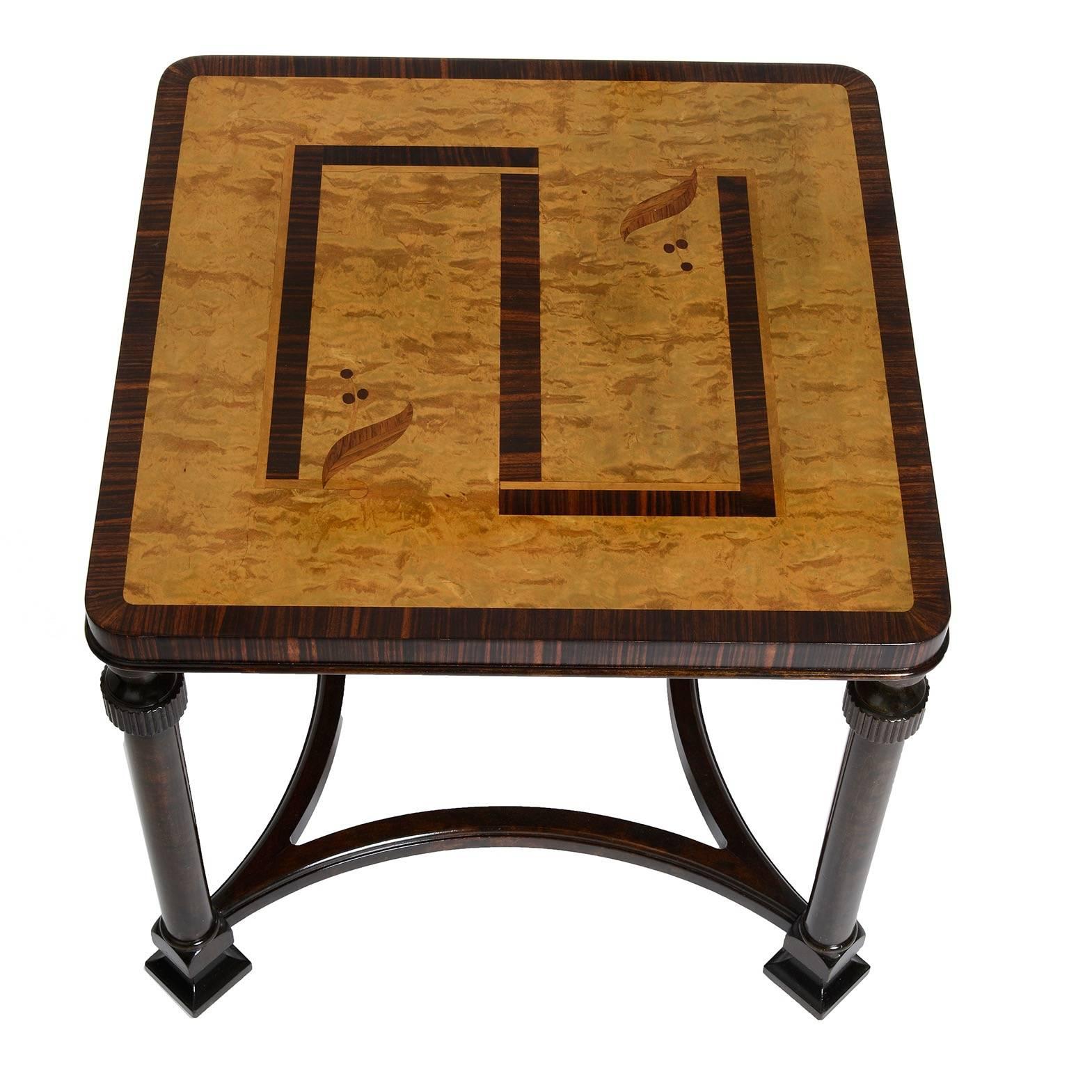 A Swedish Art Deco (Swedish Grace) side table, circa 1930s, the square geometric and foliate inlaid birch top with a palisander crossbanding, raised on circular turned legs joined by an open concave quadripartite stretcher ending with block feet.