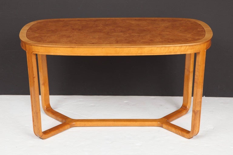 A Swedish elmroot and elm cross-banded coffee table, Circa 1930s, produced by SMF, Svenska Mobelfabriken, Bodafors,  with a oblong top raised on channeled straight legs and a continuous stretcher.
Designed by Birtil Fridgagen. - Identical table form
