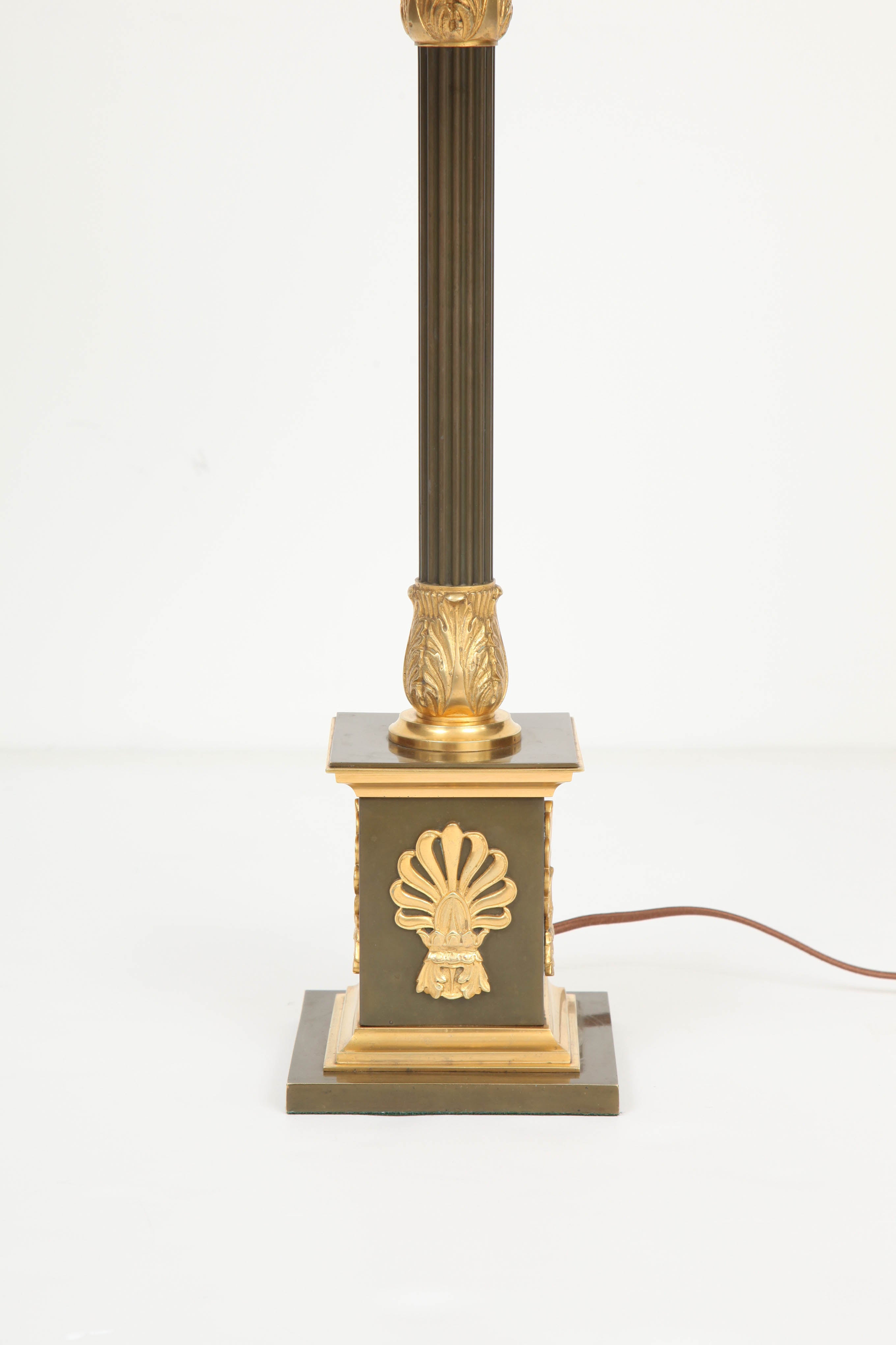 A Danish Empire gilt bronze and patinated bronze table lamp, Mid 19th Century, converted from oil to US electric, of classical firm with a fluted stem, acanthus leaf top and bottom, raised on a square pedestal with palmette leaves.