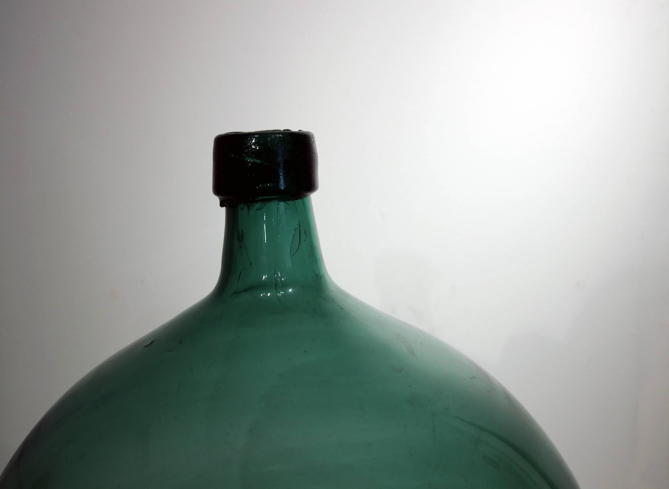 Large and fine, deep green blown glass demijohn bottle; American, late 19th century. Excellent condition. Unusual rich coloration and slightly rounded form.