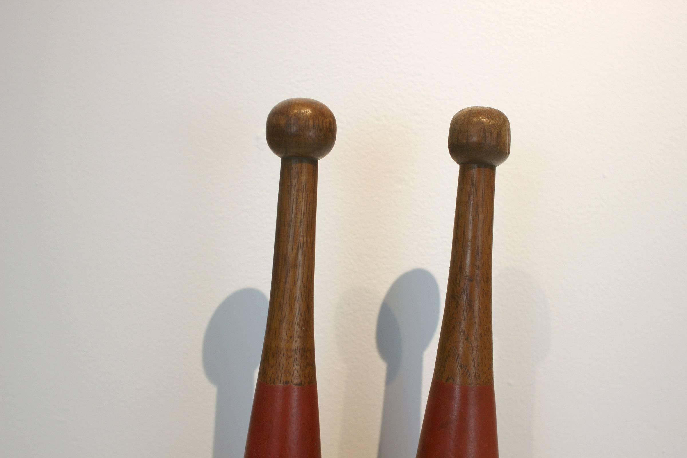 Very nice pair of turned juggling pins in original red and gold paint over oak wood, American, circa 1900.