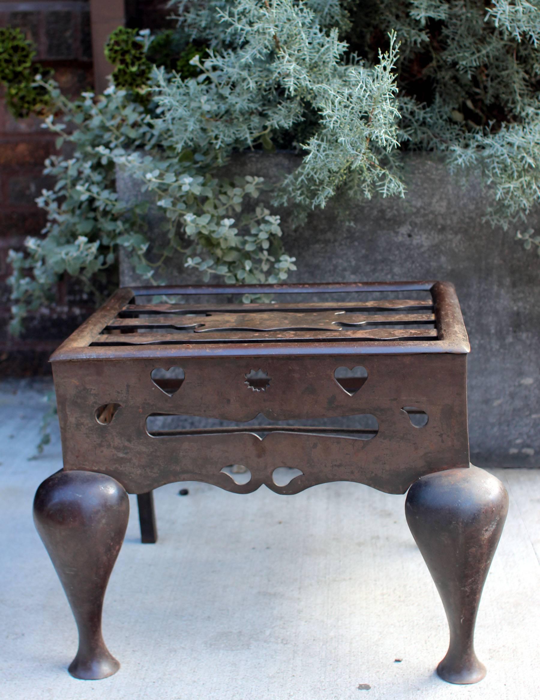 Heavy steel footman's trivet with cut decorations including hearts and handles, mid-19th century. Would work well as a small and low table. Very sturdy. Tabletop measures 12.5
