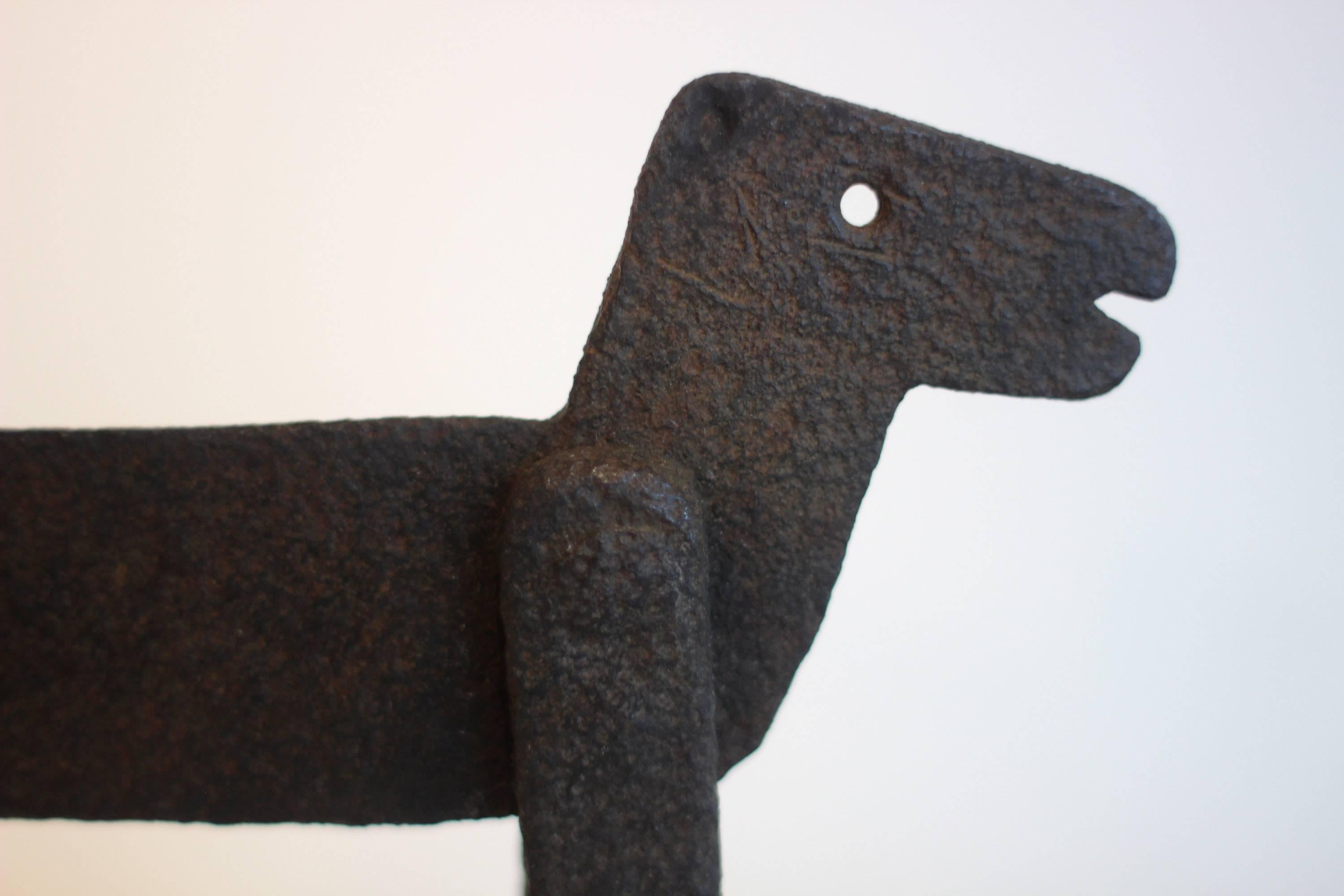 Whimsically sculptural, small, primitive boot scraper in the shape of a dog with curled 